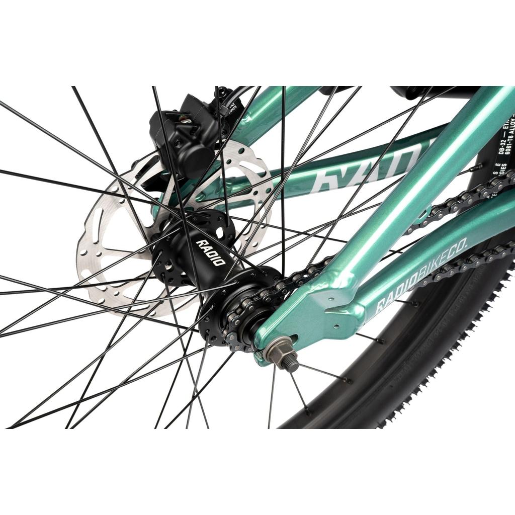 Close-up of the Radio Griffin 24 Inch Dirt Jumper’s rear wheel, showing its disc brake, black "R40D" hub, chain, and part of the turquoise frame marked "RADIOBIKECO.