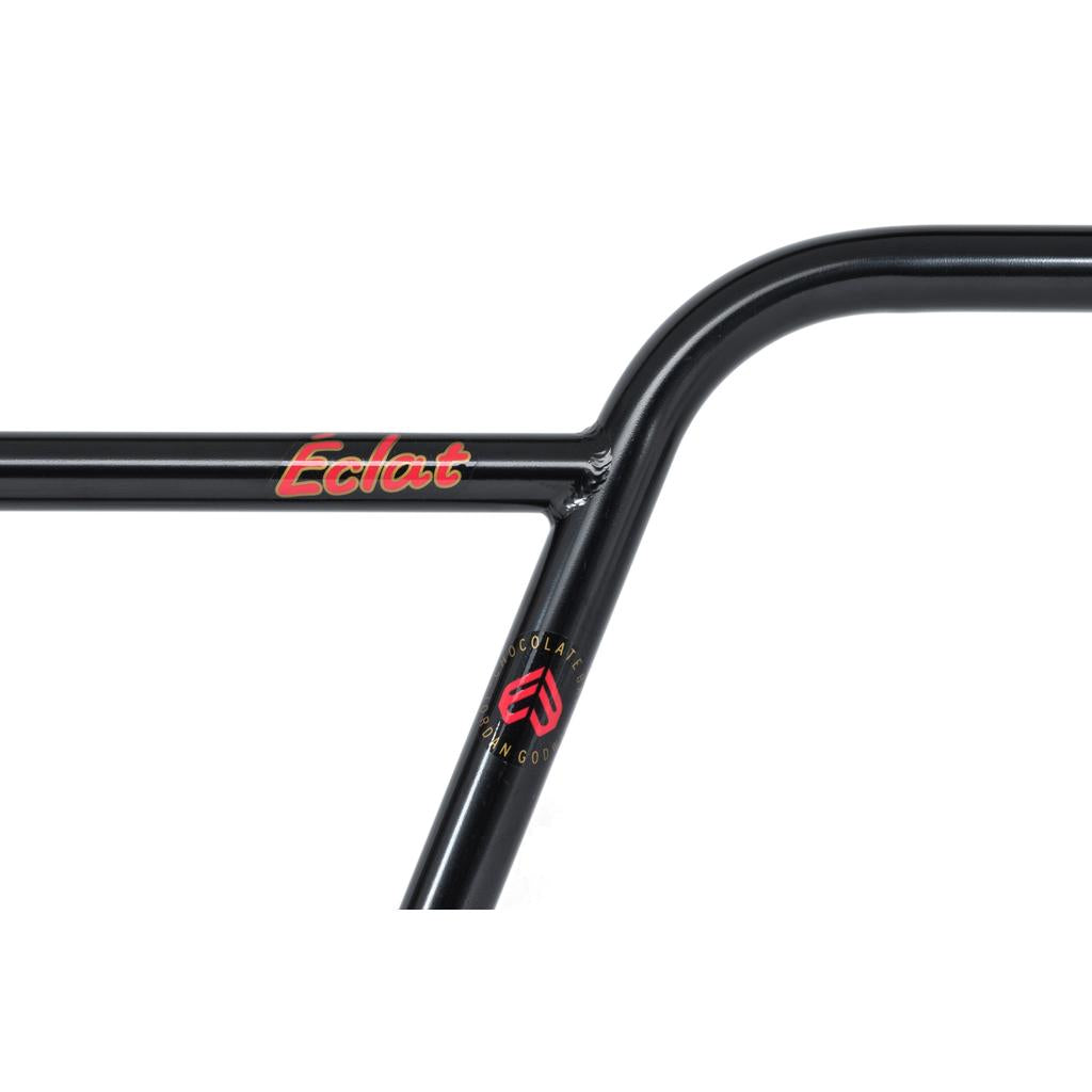 Close-up of a black BMX handlebar with “Eclat” branding in red and yellow text and a small circular logo below the crossbar, featuring the Eclat Chocolate Bars (22.2mm Clamp) from the signature Jordan Godwin series.