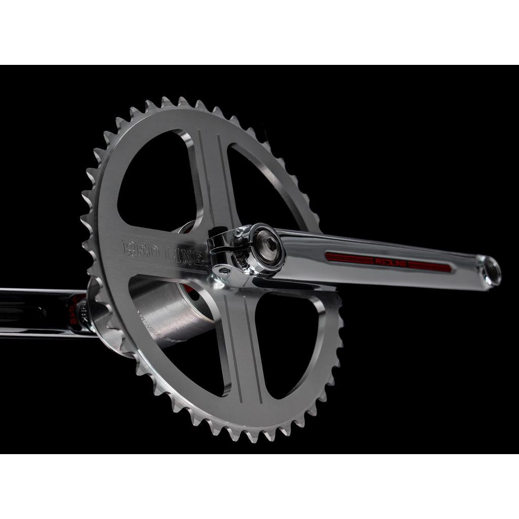 Close-up of a Redline Vintage Flight 401 Crank Set and chainring, crafted from 4130 chromoly steel with "REDLINE" branding, set against a black background.