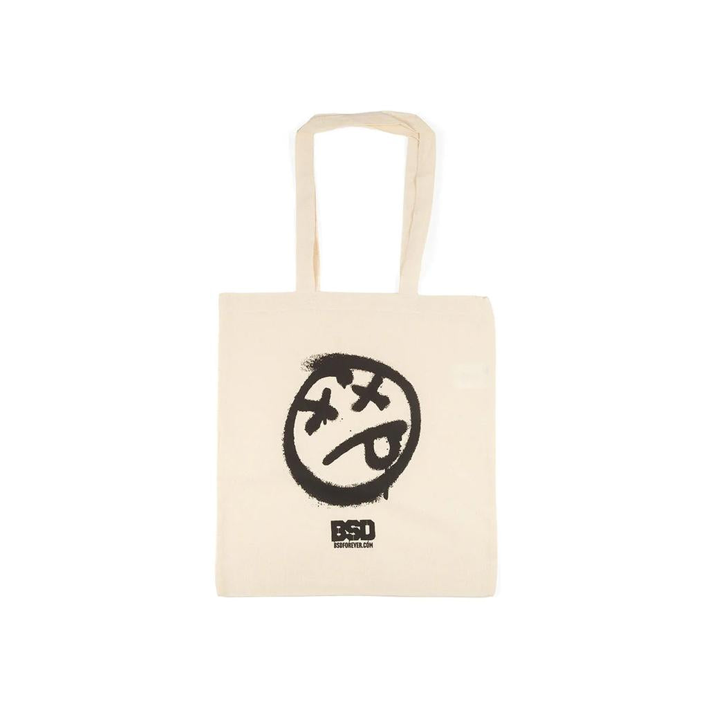 The BSD Acid Tote Bag is a beige, heavyweight cotton tote with two handles, featuring a black abstract face graphic and “BSD” with smaller text underneath.