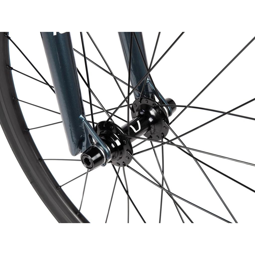 Close-up of the front wheel of the Radio Xenon Junior Disc 20 Inch Bike, featuring black spokes, a black hub, and a section of its metallic blue fork. The Tioga Power Block tyres complement the hydroformed 6061-T6 alloy frame.