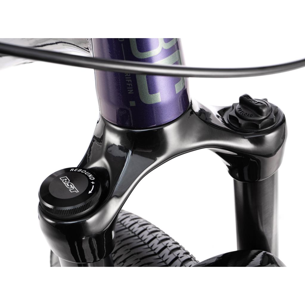 Close-up of the Radio Griffin 26 Inch Bike’s front suspension fork, showing the adjustment knobs, part of the tire, and Tektro Disc Brakes.