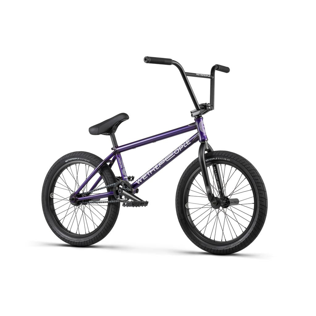 The Wethepeople Reason Shift 20 Inch Bike is a premium BMX with a full chromoly frame, black tires, black seat, and silver pedals. Shown in purple from the side on a white background.