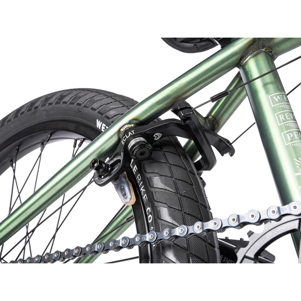 Close-up of a green Wethepeople Revolver 20 Inch Bike frame showing the rear tire, chain, and black Eclat brake caliper—demonstrating quality aftermarket components.
