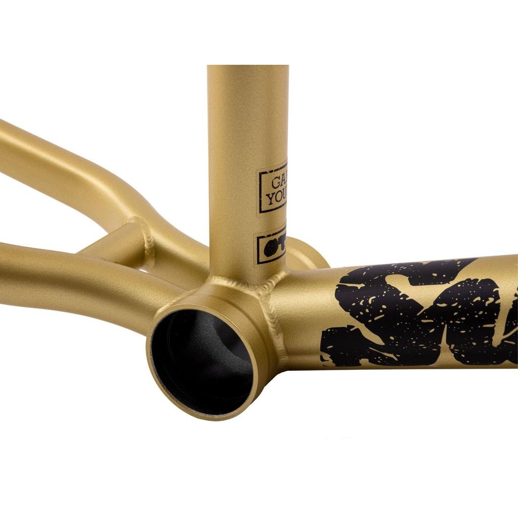 Close-up of the Sunday Wavelength Frame in metallic gold 4130 chromoly, highlighting the bottom bracket area with visible welds and bold black graphics.