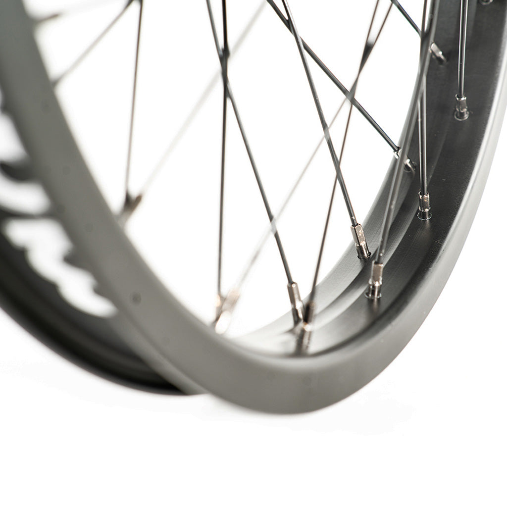 A close up of a black stainless steel-spoked bicycle wheel with a Colony Pintour 18 Inch Front Wheel rim.