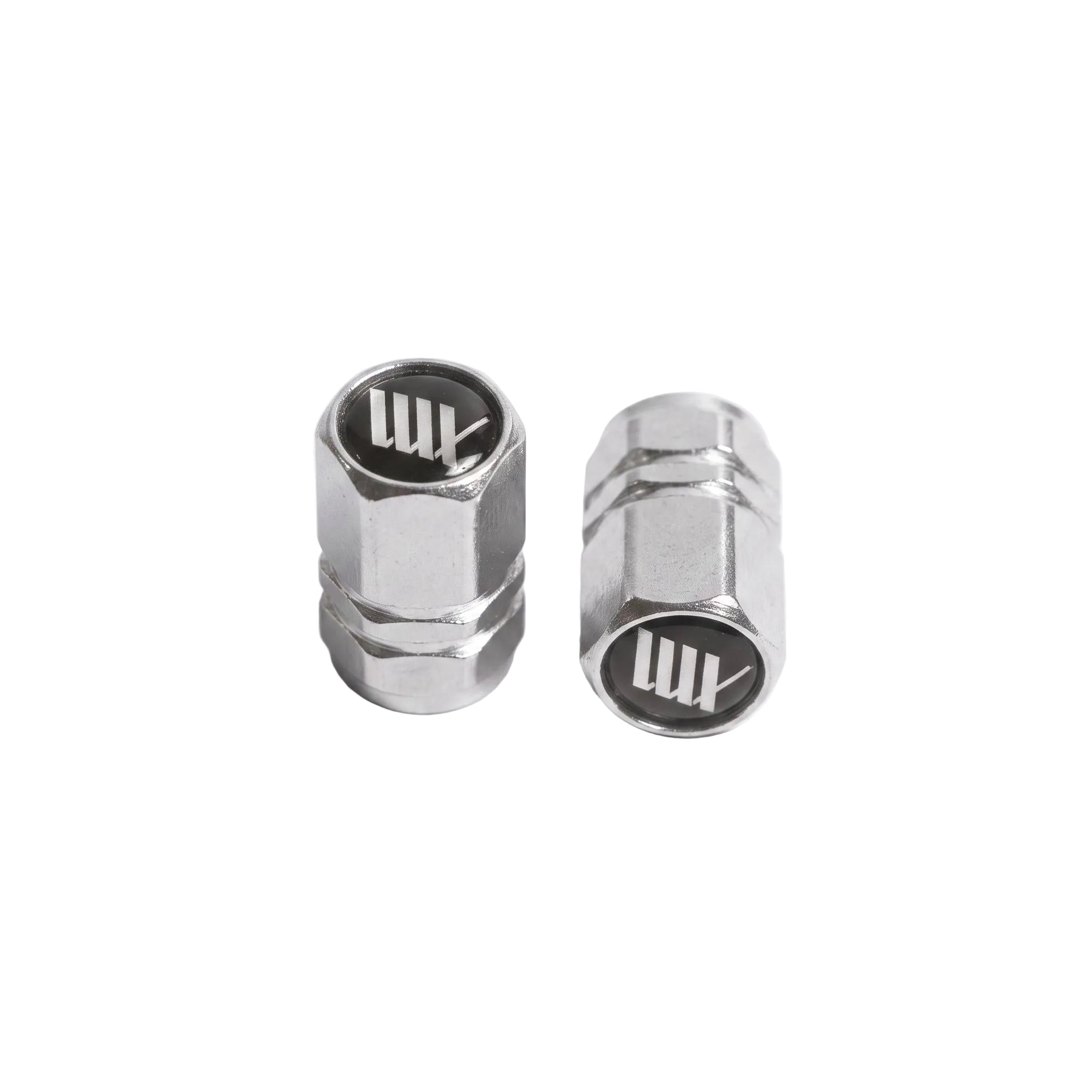 Two LUXBMX Hex Logo Alloy Valve Caps stand upright on a white surface, each resembling machined metal and featuring the LUX logo on top.