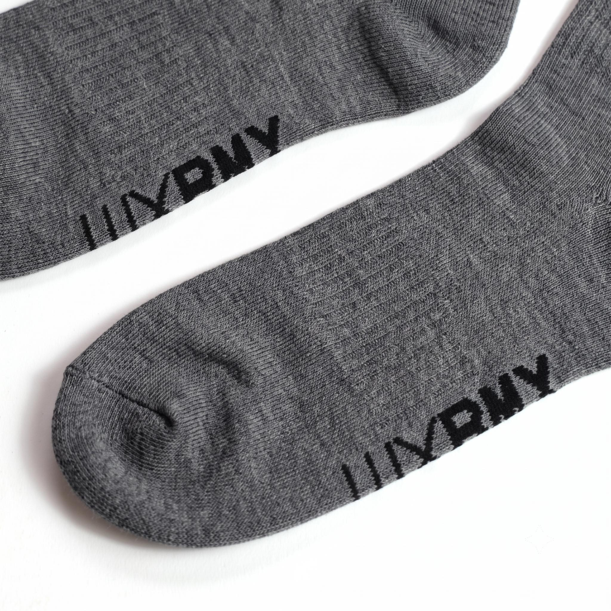 A pair of LUXBMX Crew Socks in gray, made from a durable bamboo blend and featuring the letters "UXPNY" in black near the toes, displayed on a white surface.