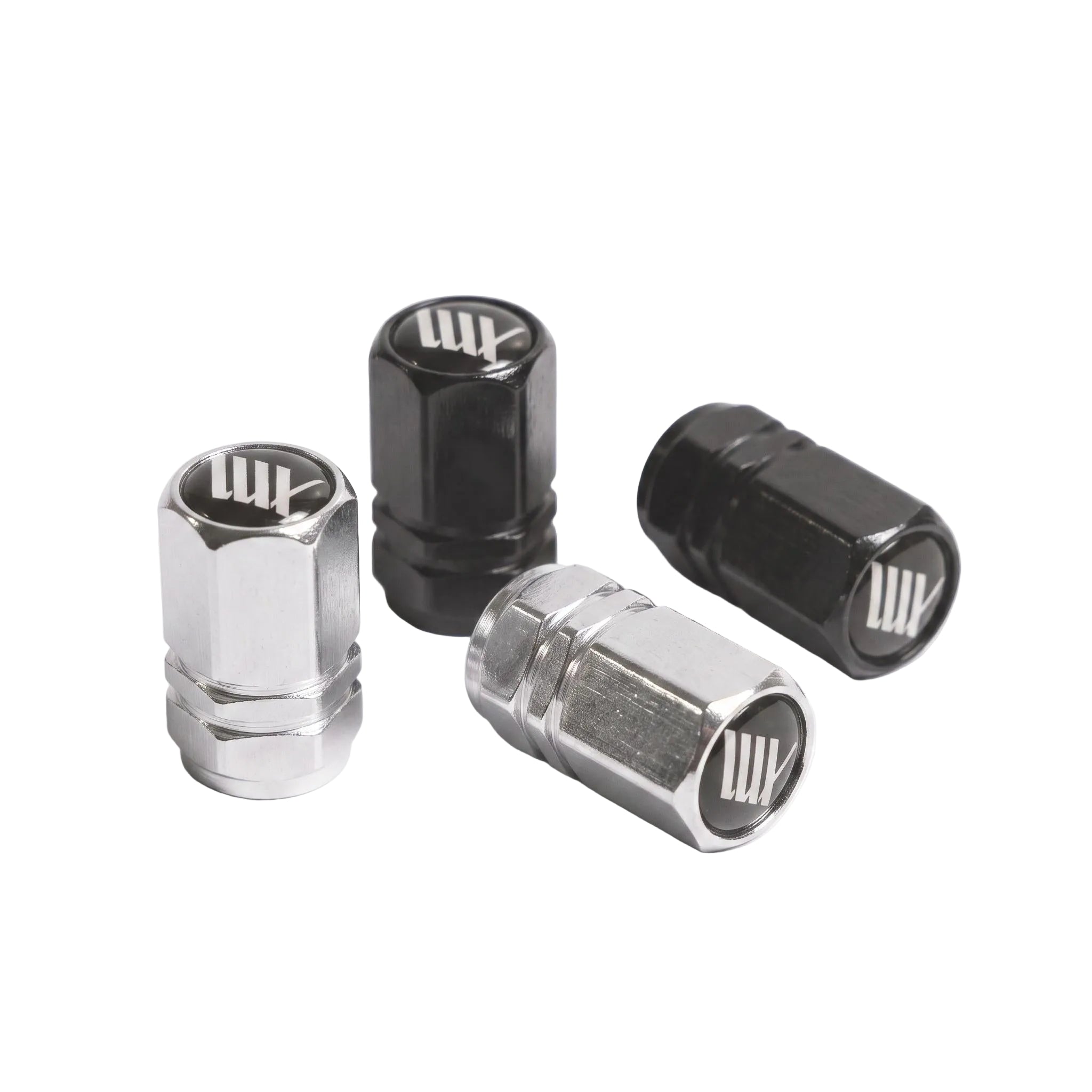 Two silver and two black LUXBMX Hex Logo Alloy Valve Caps are displayed on a white surface. Each cap features a stylized white "LW" logo on top, making these pairs standout bike accessories.