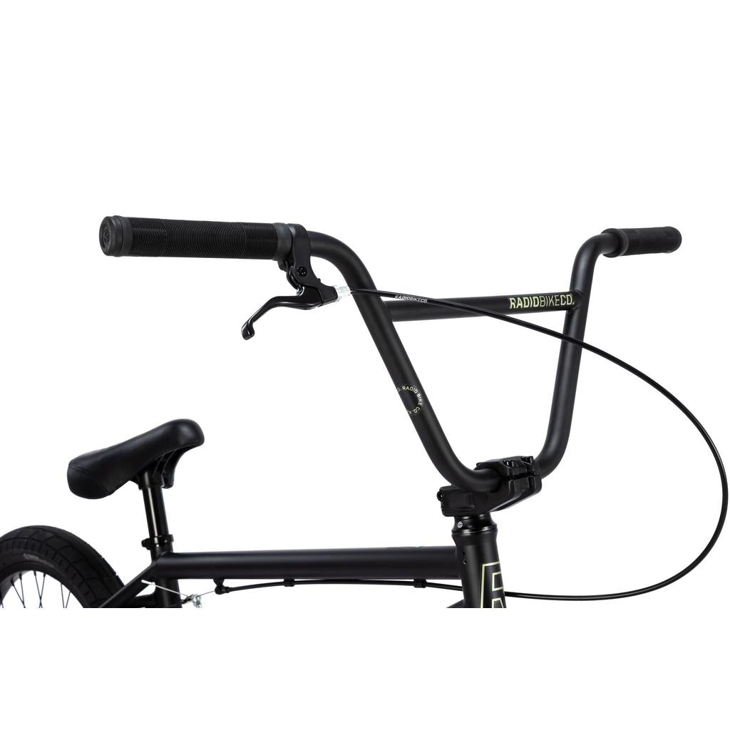 Close-up of the black Radio Evol XL 20 Inch Bike's handlebars, brake lever, and front brake cable, with part of the seat and rear wheel visible.