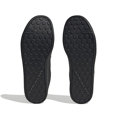 A pair of black Five Ten Freerider Pro Flat Core Shoes soles with circular treads and "STEALTH" embossed diagonally, designed to deliver pedal-gripping control for mountain biking.