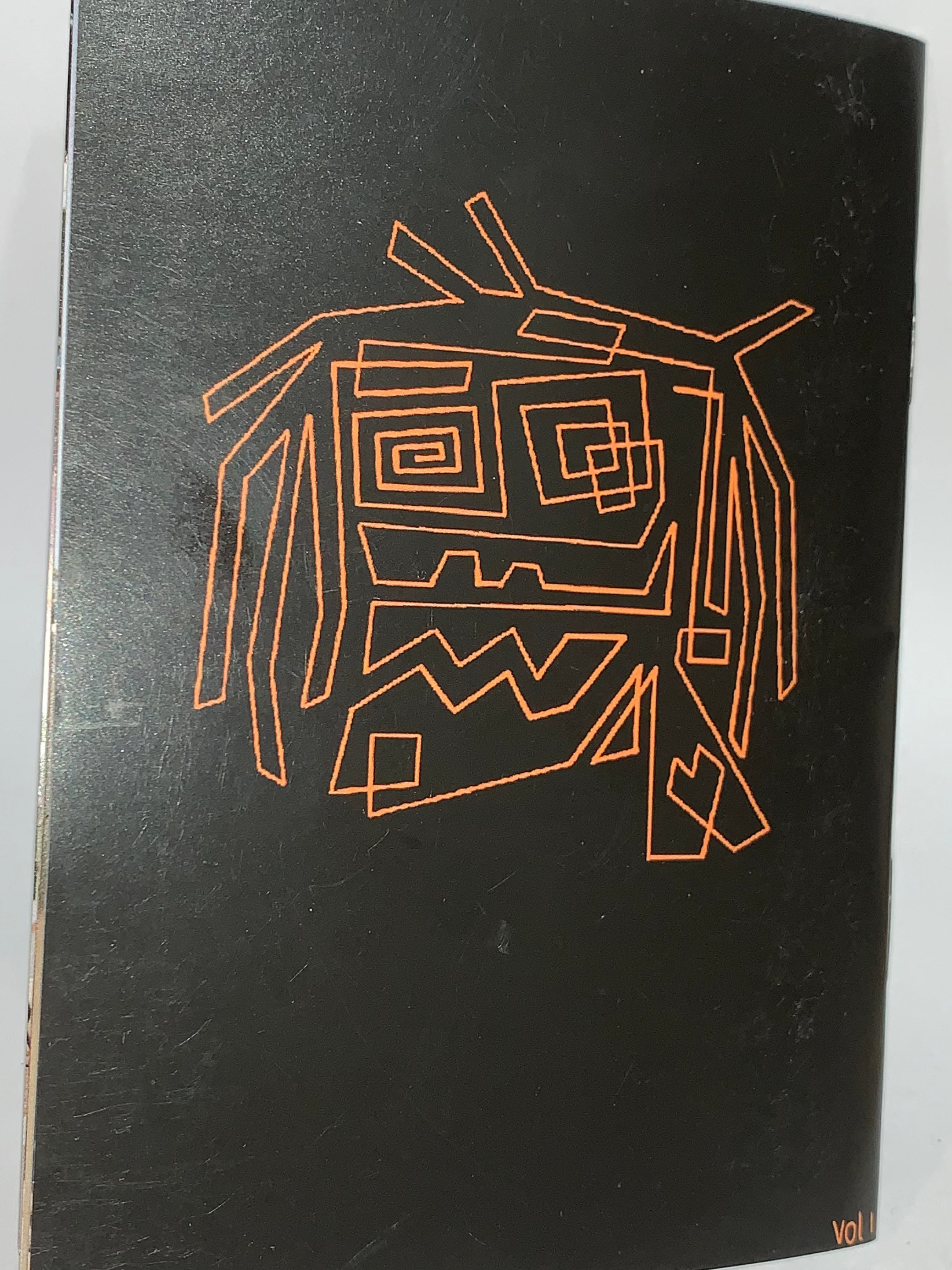 Jerk Zine Volume 1 features a black cover with an abstract orange face, accented by geometric shapes and lines. Inspired by BMX riders at Kirkham Skate Park, "VOL I" appears in the bottom right corner.