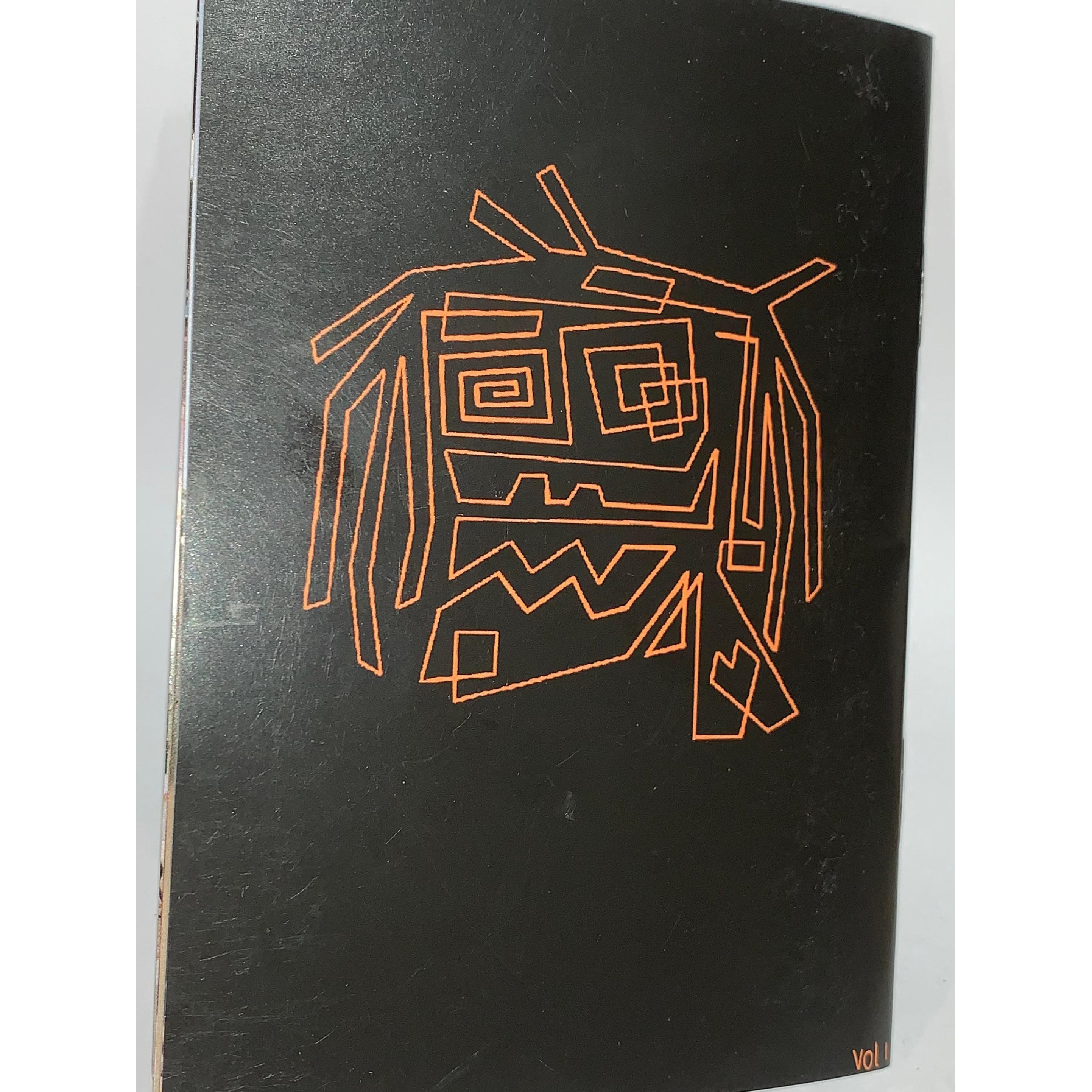 Jerk Zine Volume 1 features a black cover with an abstract orange face, accented by geometric shapes and lines. Inspired by BMX riders at Kirkham Skate Park, "VOL I" appears in the bottom right corner.