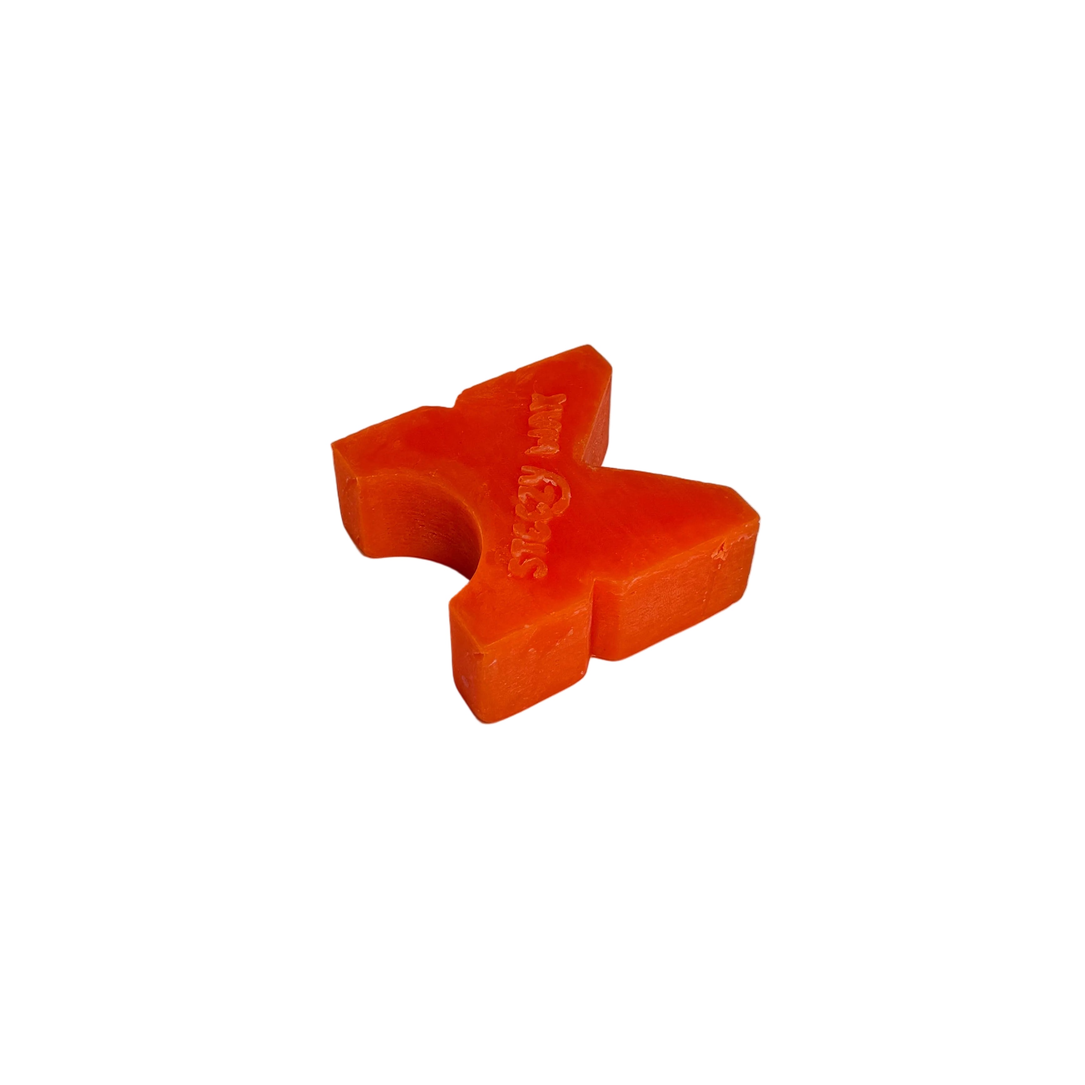 A Steezy Wax / K-Slide, shaped like an orange cross, sits on a plain white surface with a neutral gray background.