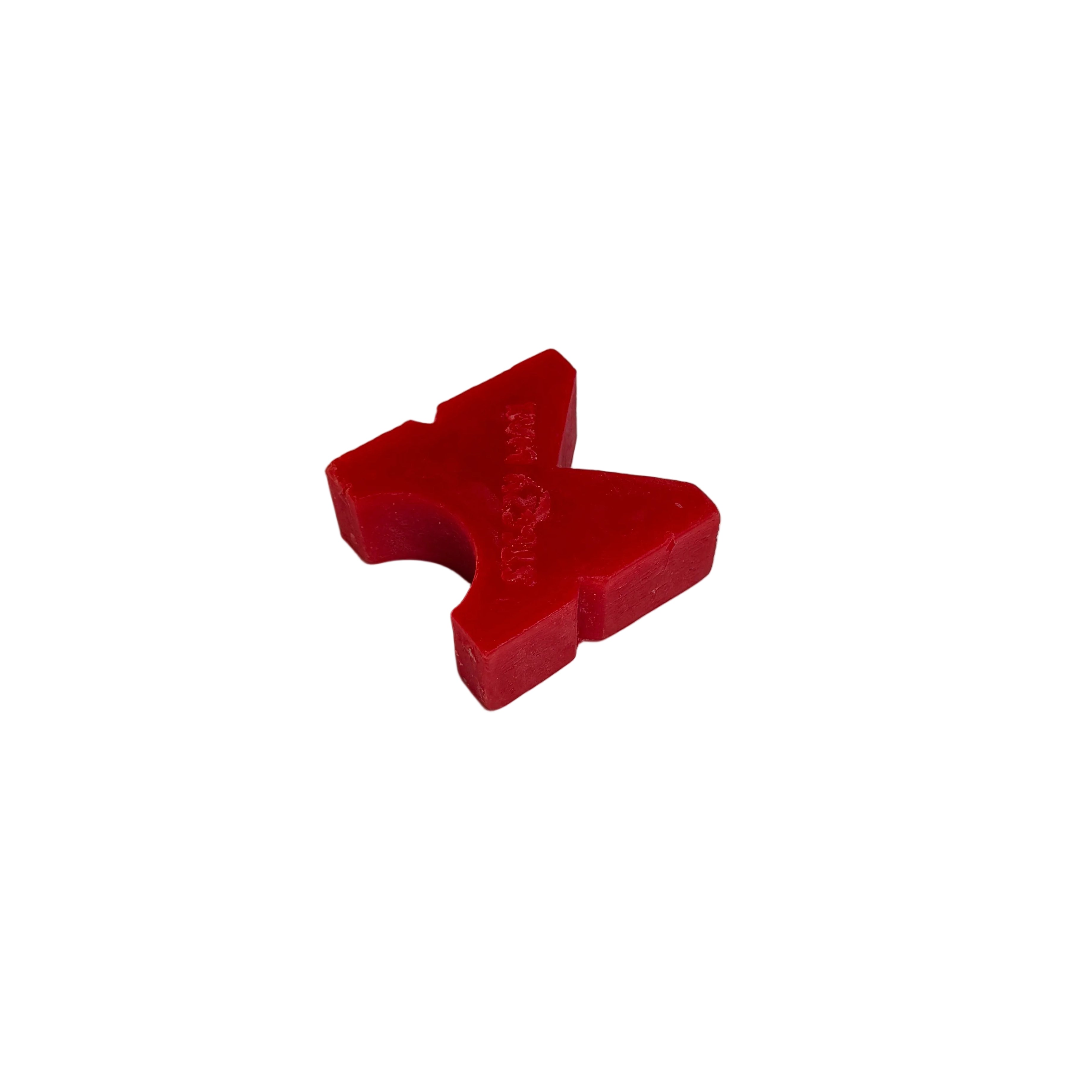 A red, X-shaped Steezy Wax K-Slide block rests on a white surface with a gray background, highlighting the quality of handmade Australian skate wax.