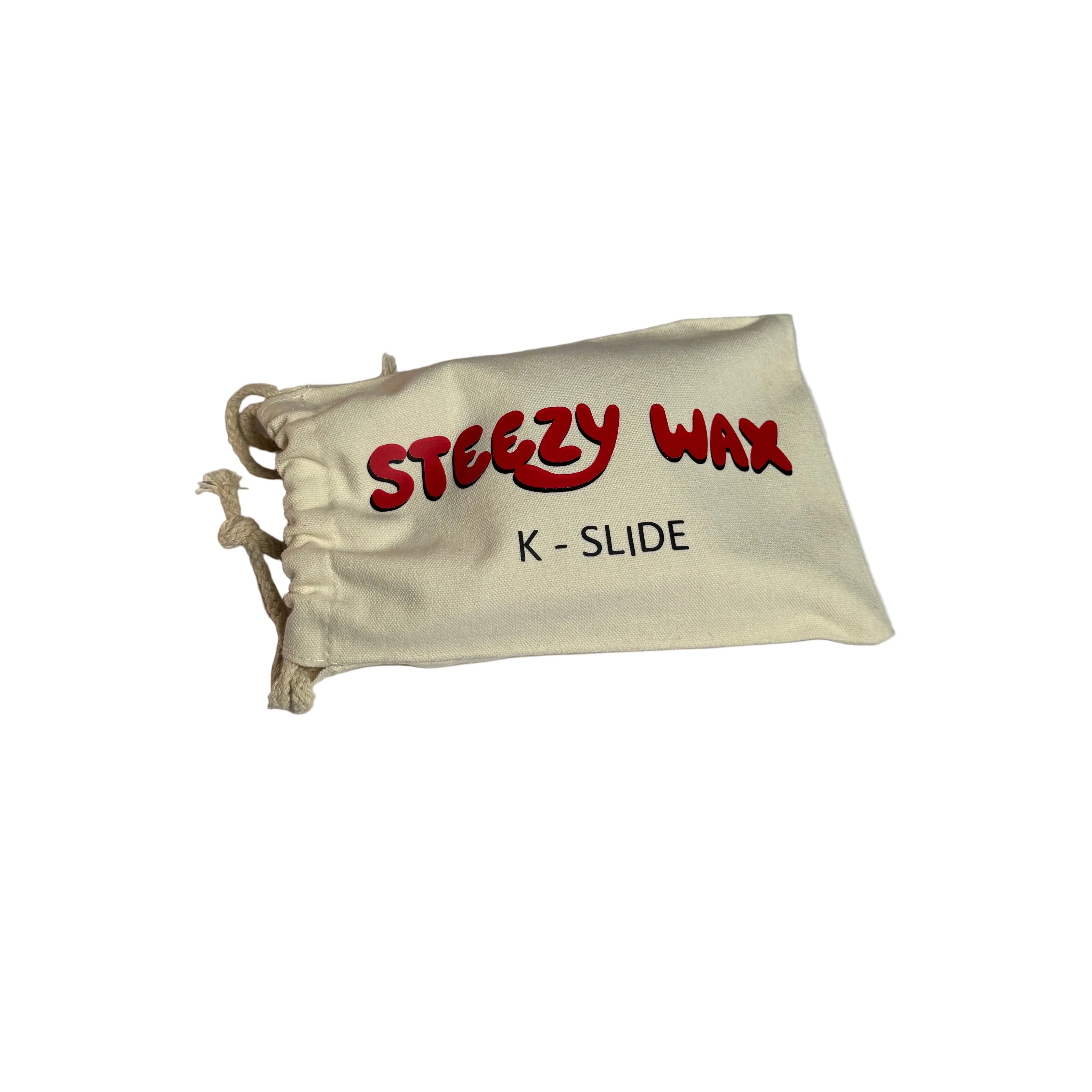 A compact drawstring bag labeled "Steezy Wax / K-Slide" sits on a white surface, ready to hold your favorite skate wax block—ideal for skaters across Australia.