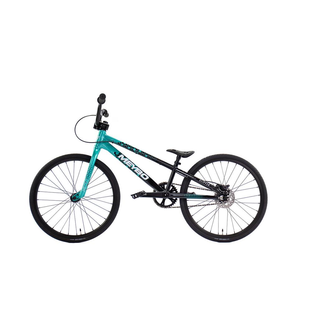 Side view of the Meybo 2026 Clipper Junior Bike in teal and black, with a lightweight frame, flat pedals, and thin tires, displayed against a plain white background.