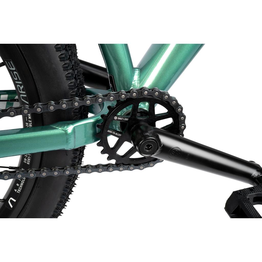 Close-up view of the Radio Griffin 24 Inch Dirt Jumper Bike’s crankset, chainring, and chain, showcasing its metal frame and tire.