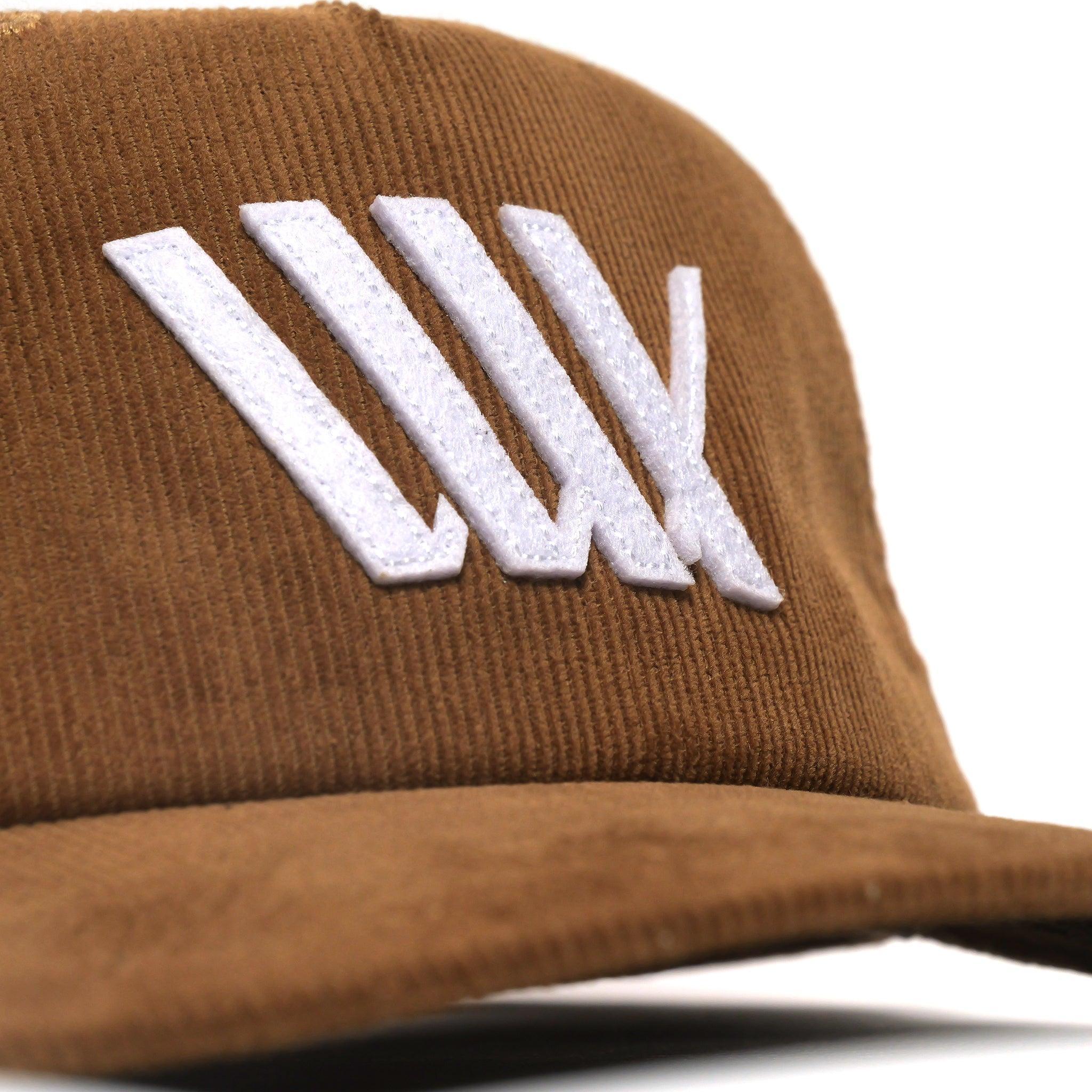 Close-up of the LUXBMX Outfield Cap Brown, a brown corduroy baseball cap with a white embroidered LUX logo on the front.