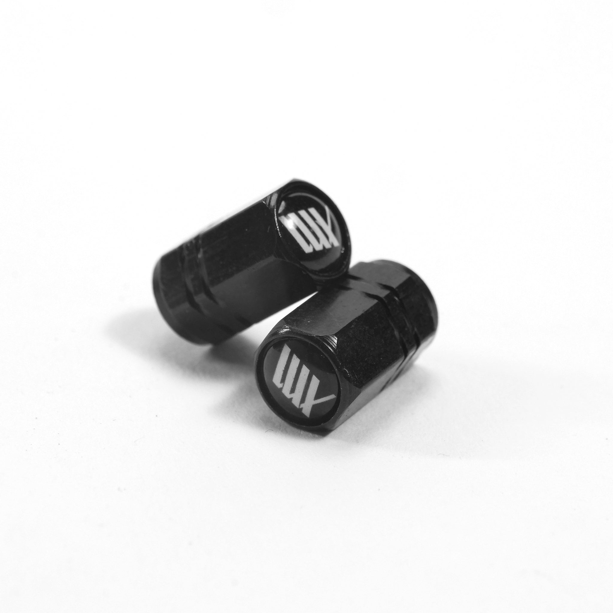 A pair of LUXBMX Hex Logo Alloy Valve Caps in black, featuring white "MT" logos, made from machined alloy—ideal BMX accessories shown on a white surface.