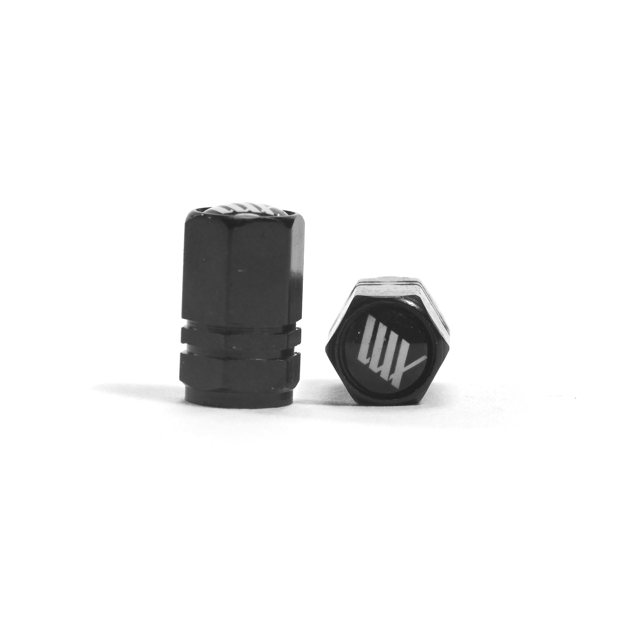 The LUXBMX Hex Logo Alloy Valve Cap (Pair) features black hexagonal alloy caps with a white stylized logo, making them a sleek addition to your BMX accessories.