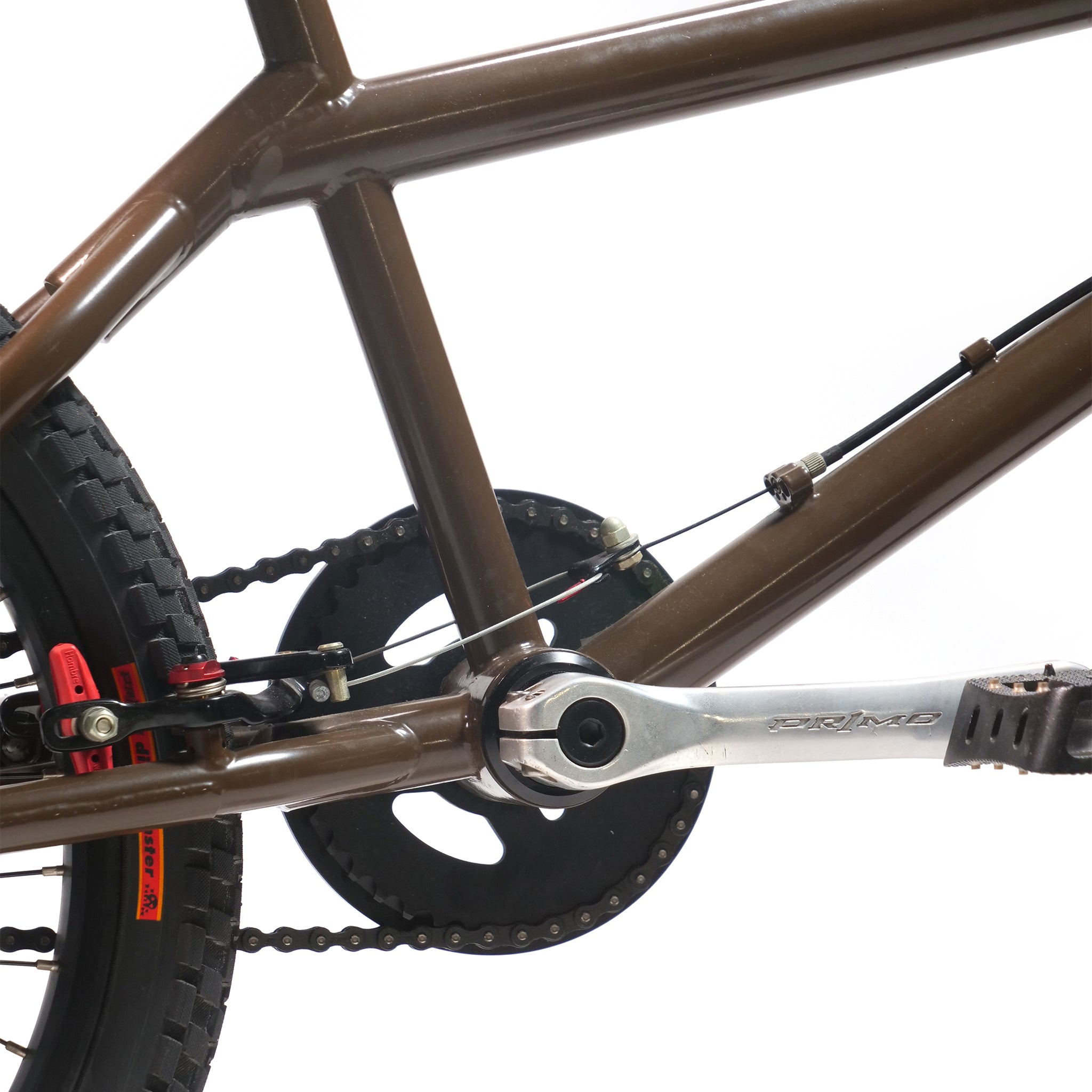 Close-up of a brown Terrible One Barcode Garrett Byrnes Custom 20 Inch Bike (2003) frame, showing the rear wheel, chain, pedal, crank arm, and part of the brake system against a white background.