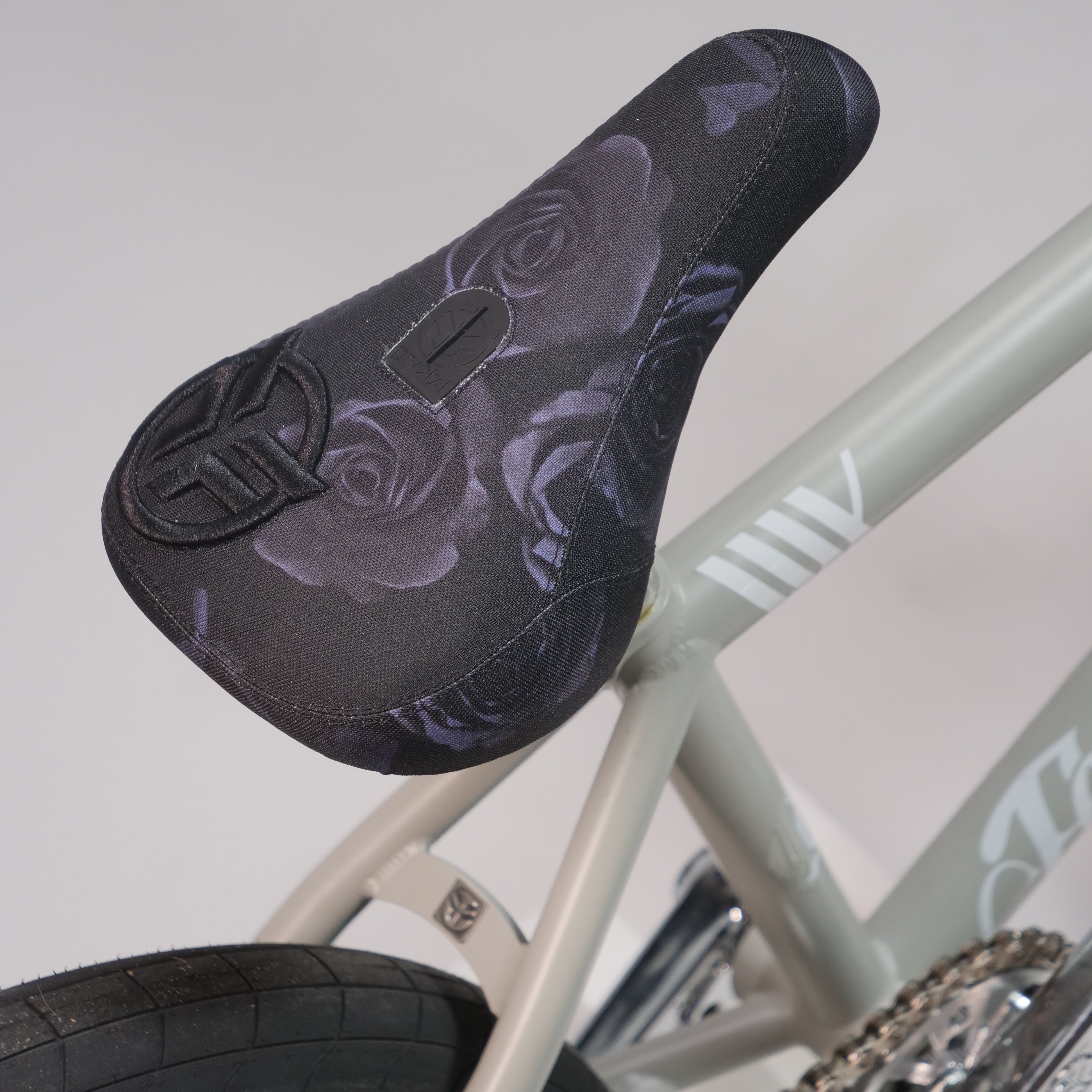Close-up of the Federal Lacey x Chrome Custom 20 Inch Bike showing a black floral rose seat with a peace symbol, mounted on a light-colored frame featuring Federal Vice 2 Cranks.