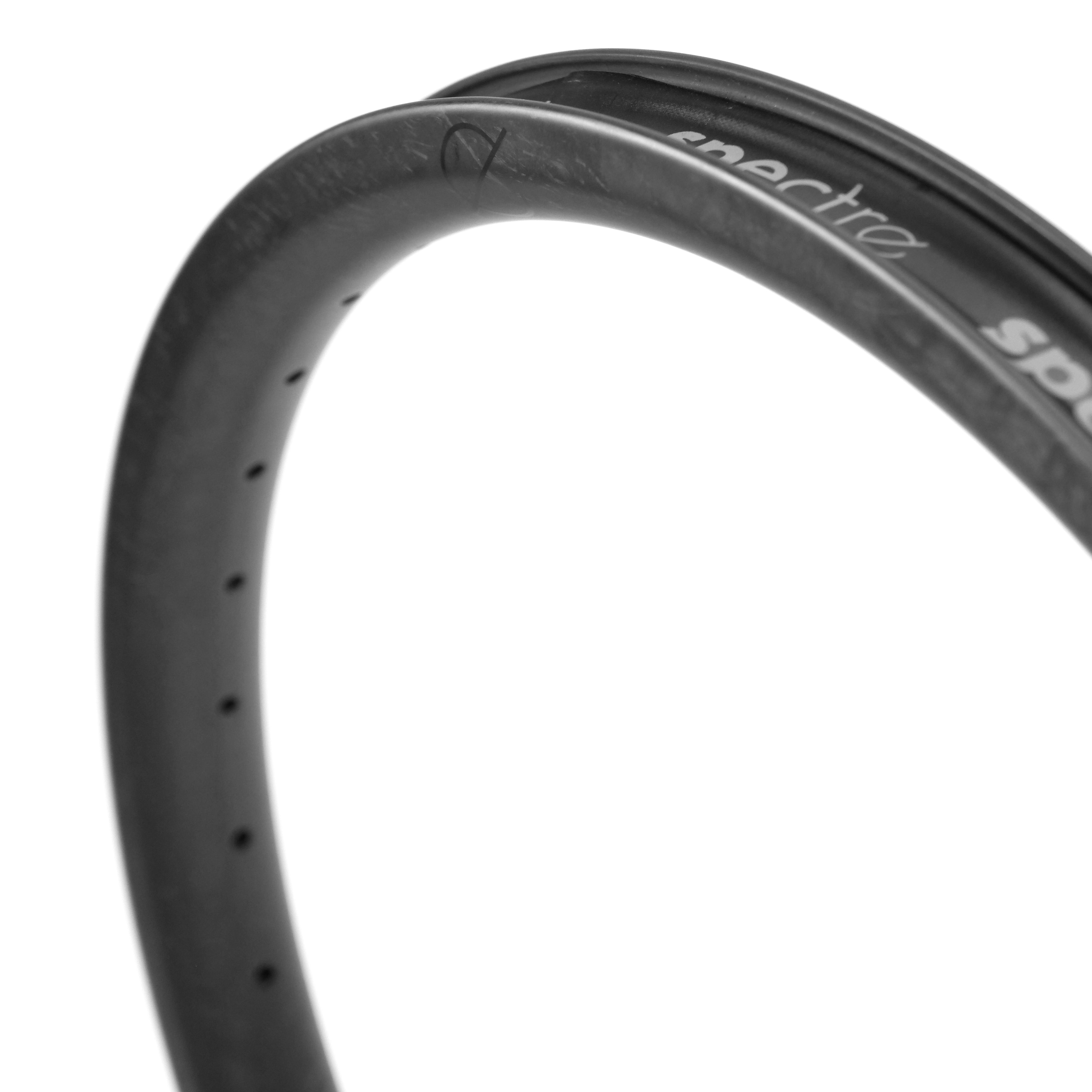 Close-up of the Spectre V3 Carbon Fiber 20 Inch 36H Brakeless Rim, made from Toray T800 carbon fiber, with 4D drilled holes and partial "spectra" text on its tubeless compatible surface.