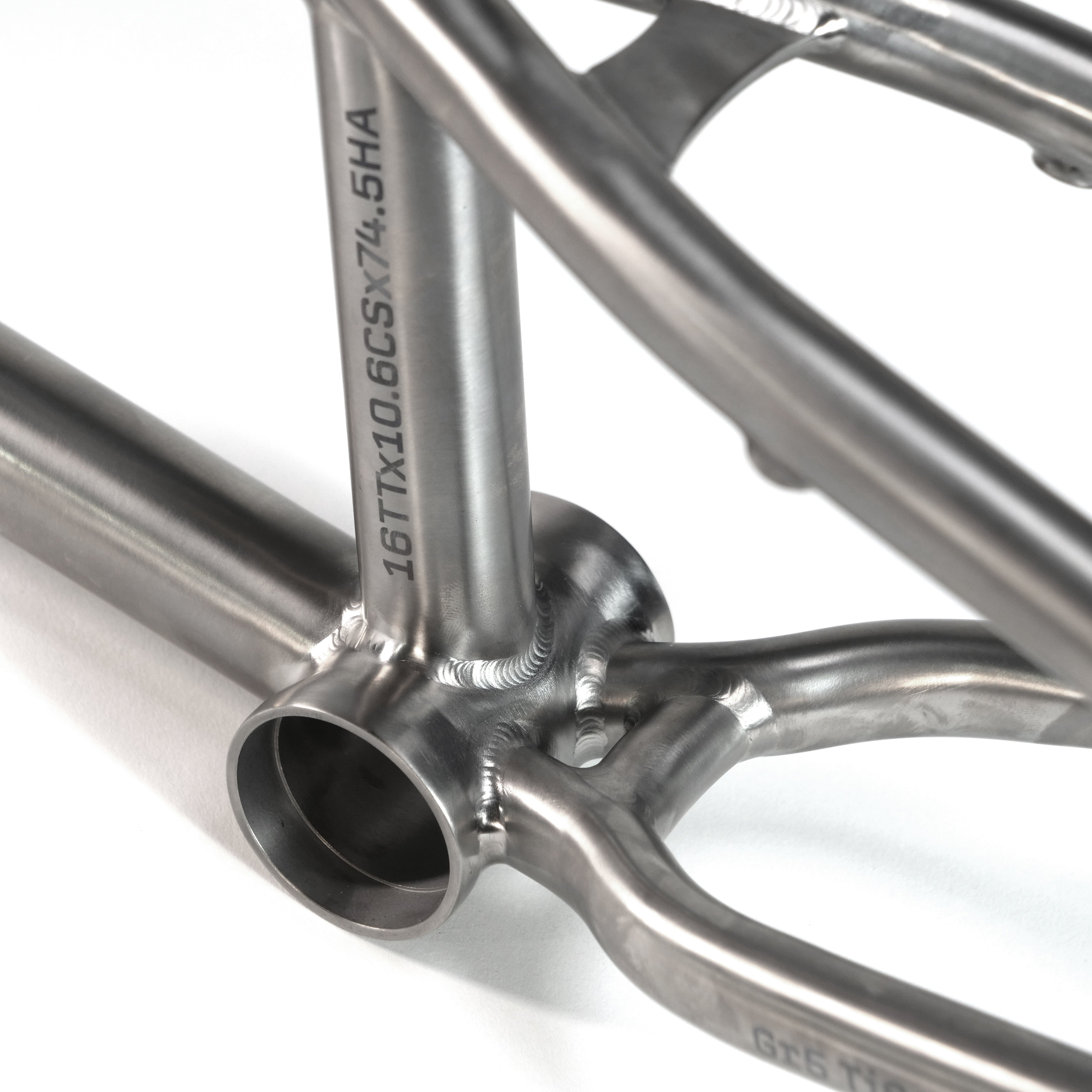 Close-up of the ION BMX Ti16 Titanium 16 Inch Frame’s bottom bracket, showcasing precise welds and engraved alphanumeric codes on the lightweight Gr5 titanium tubing.