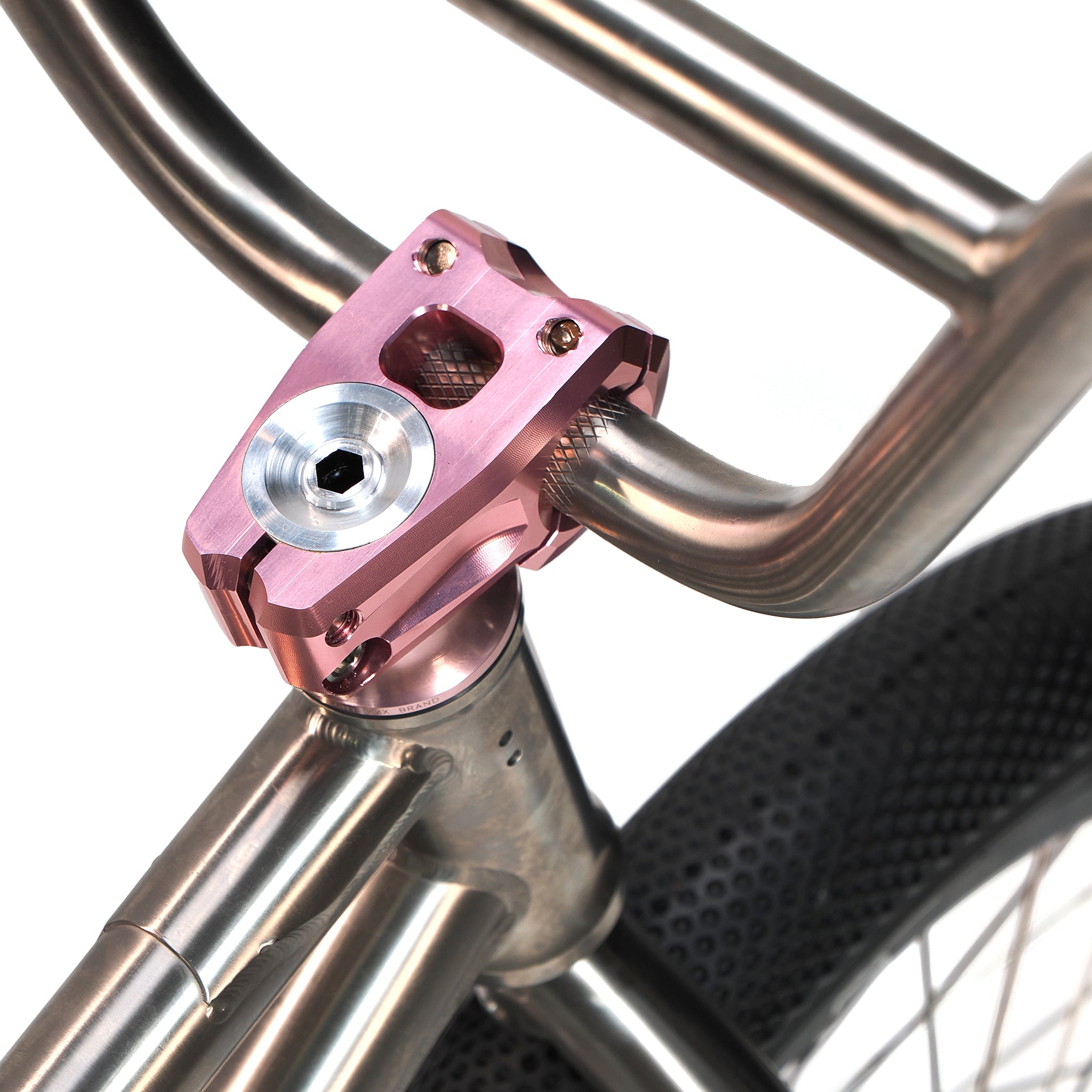 Close-up of the ION BMX Ti18 Custom Titanium 18 Inch Bike handlebar with a metallic pink stem, silver bolts, brushed titanium frame, and a knobby front tire—ideal for lightweight freestyle BMX riding.