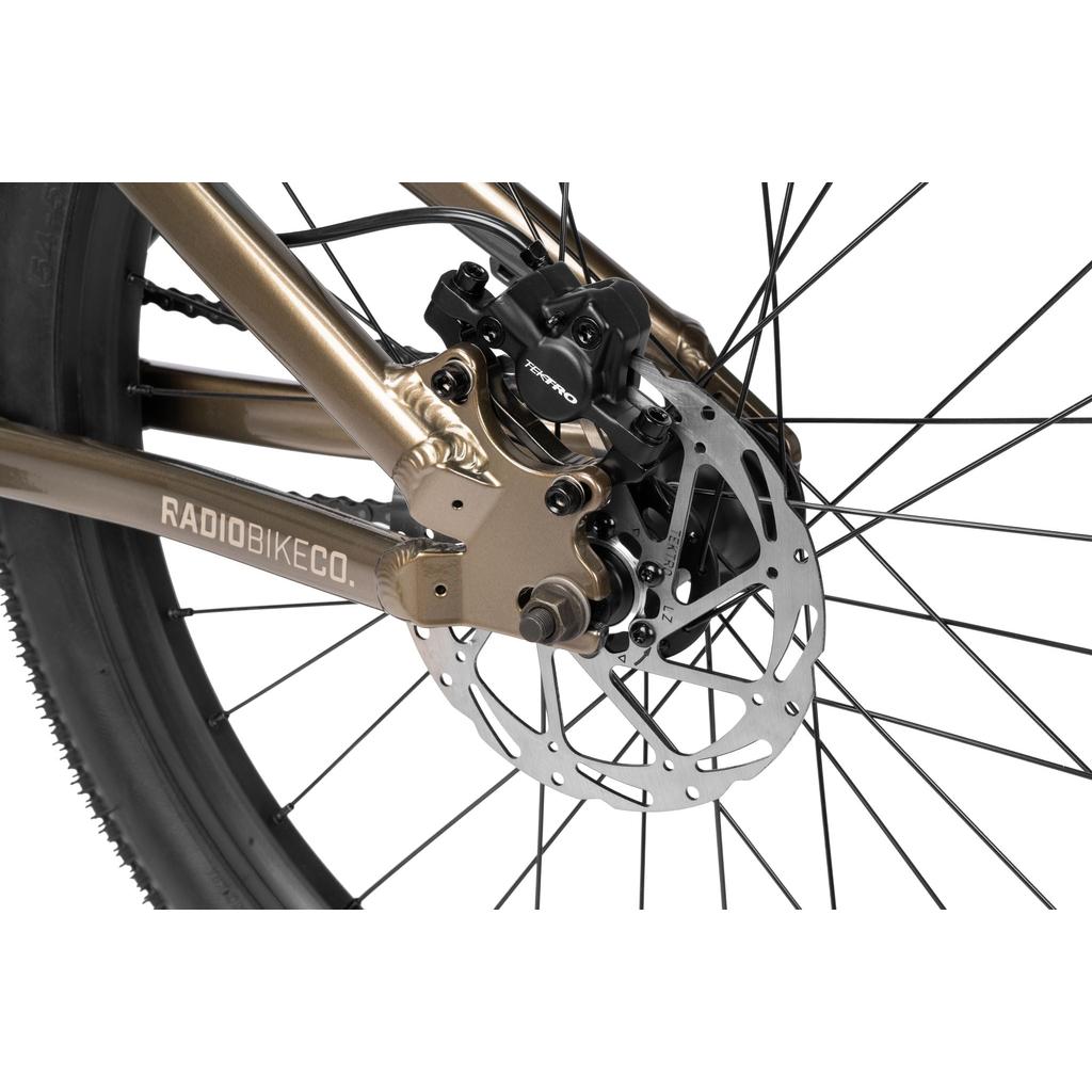 Close-up of the Radio Griffin 24 Inch Dirt Jumper Bike’s rear wheel, featuring an aluminum frame, disc brake system with a black caliper, silver rotor, and part of the frame labeled "RADIOBIKECO.