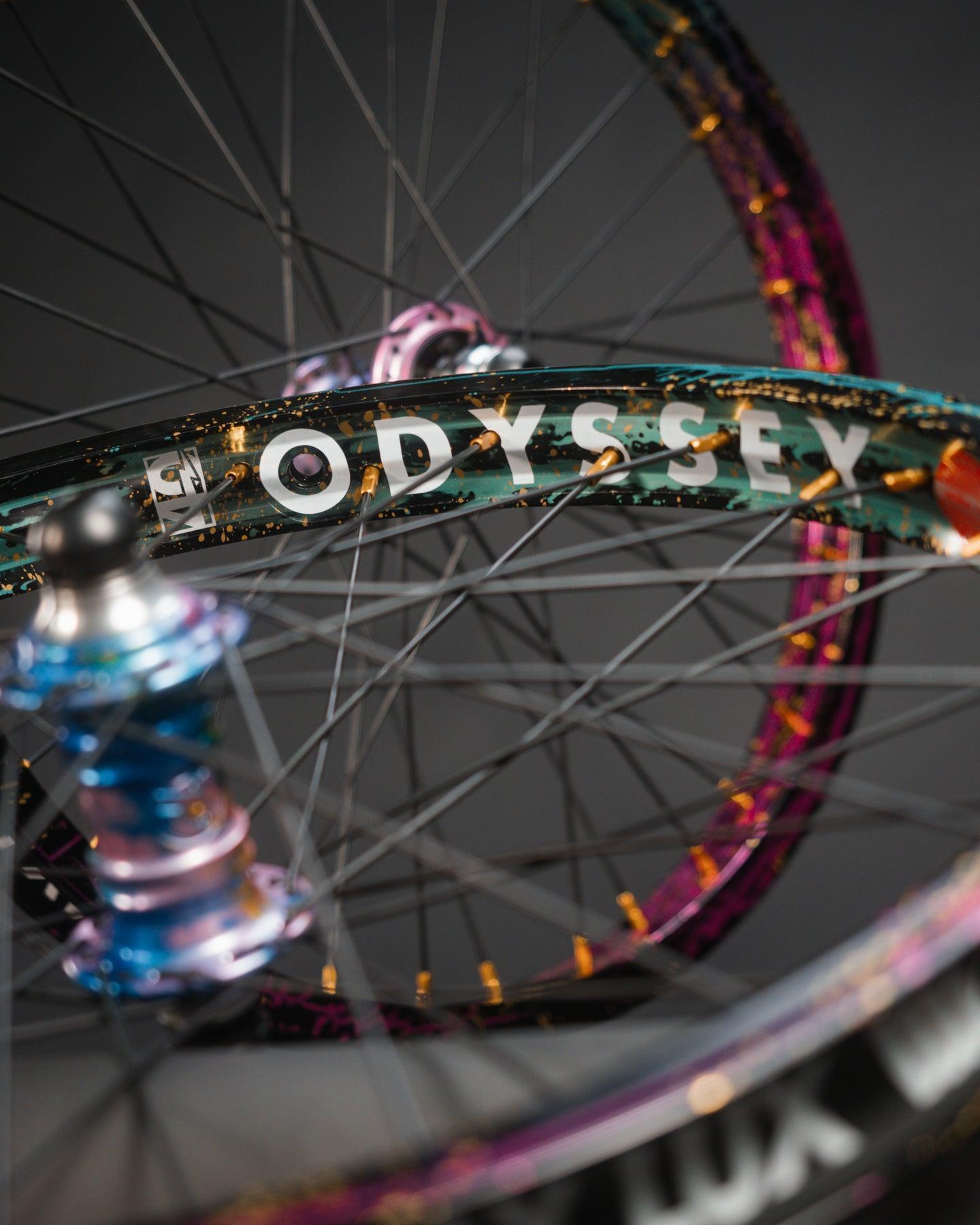 Close-up of two bicycle wheels with colorful rims; the limited edition Profile x Odyssey Near Earth Objects Wheel Set is prominently displayed, highlighting this BMX hub and Right Hand Drive setup.