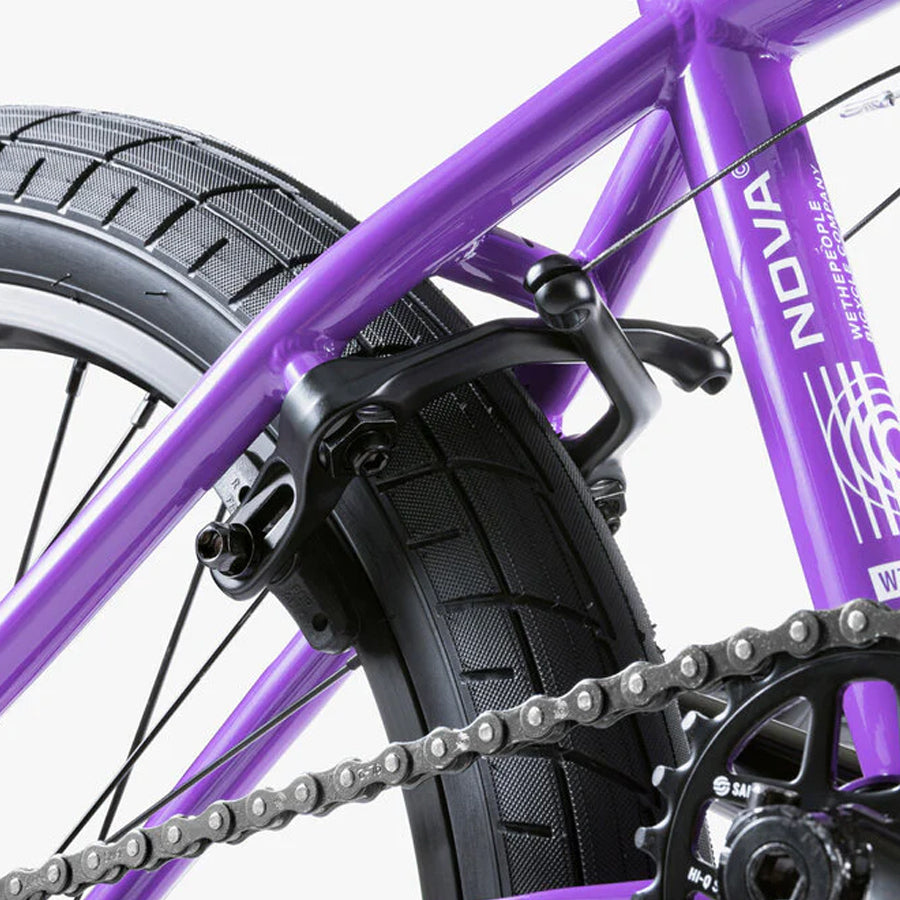 A close up of a purple Wethepeople Nova 20 Inch BMX Bike with a chain.