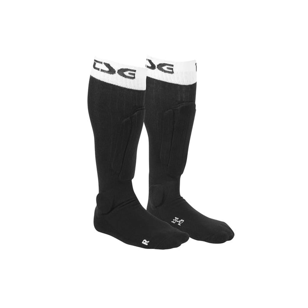 A pair of black TSG Riot Socks with white tops, "TSG" logo, reinforced shin foam, ankle padding, and labeled "R" and "L" for each foot.