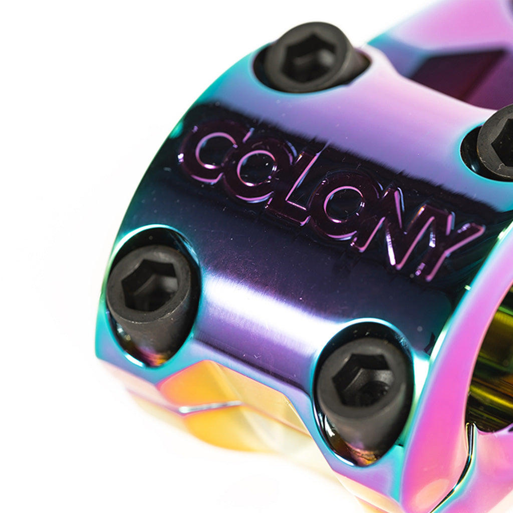 A rainbow colored bicycle stem with the word Colony Variant 52mm BMX Stem on it, a low-rise alternative to top load stems.