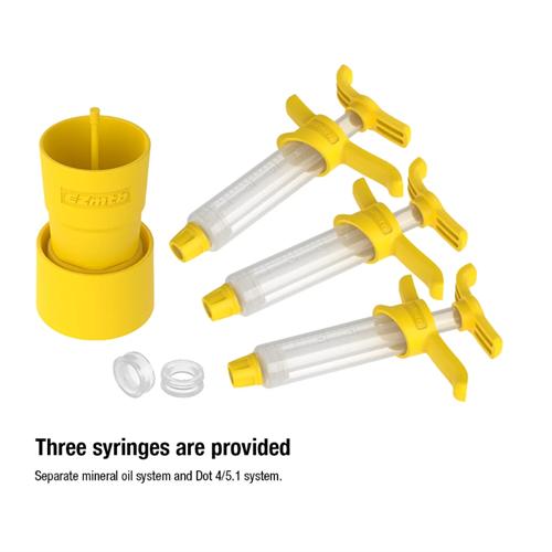 Three yellow syringes, a yellow container, and two small clear caps are shown on a white background. The text notes that three syringes come with the EZMTB Universal Brake Bleed Kit - Pro Model for oil system maintenance.