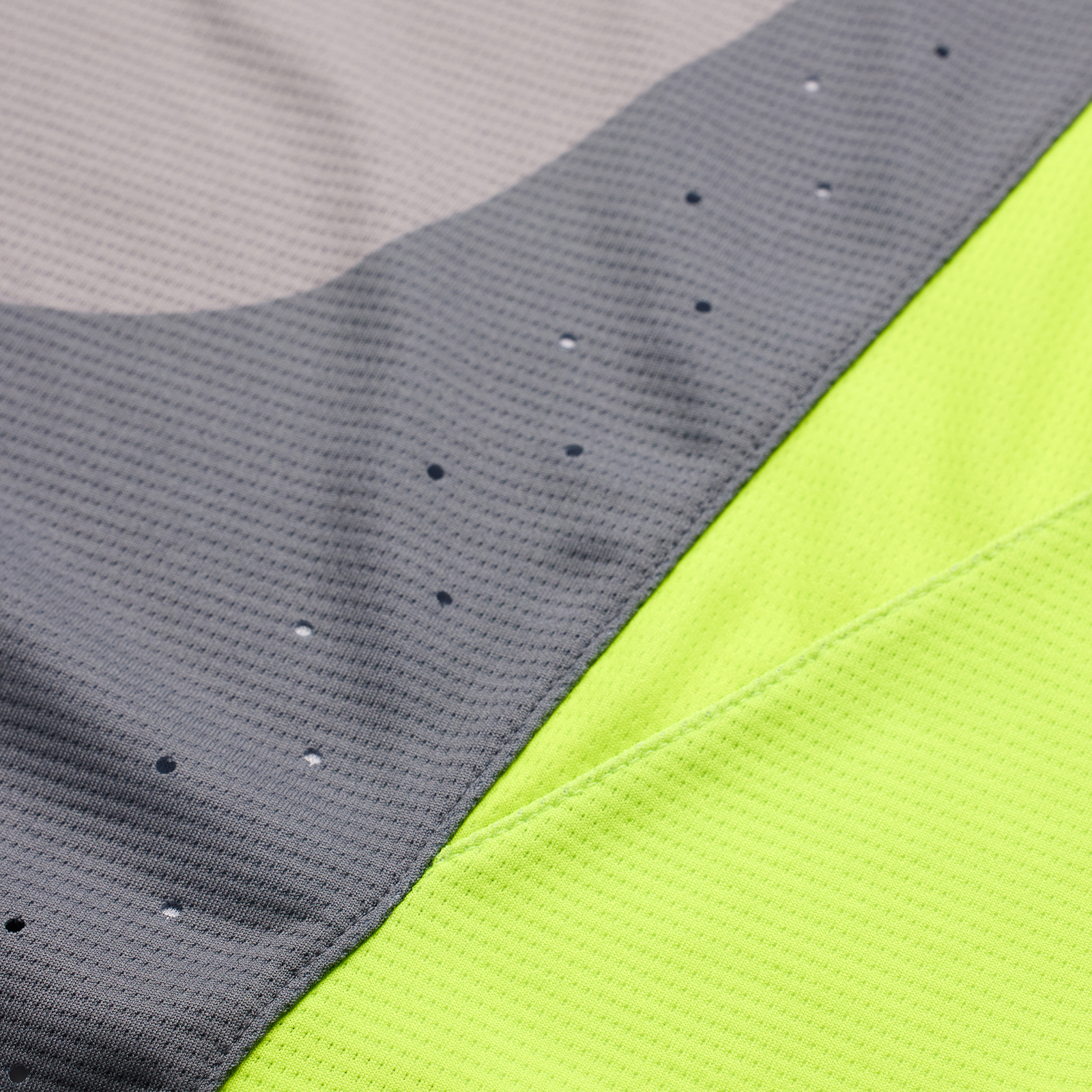 Close-up of a grey and neon yellow TLD Youth Sprint Jersey Reverb Charcoal sports fabric with ventilation holes.