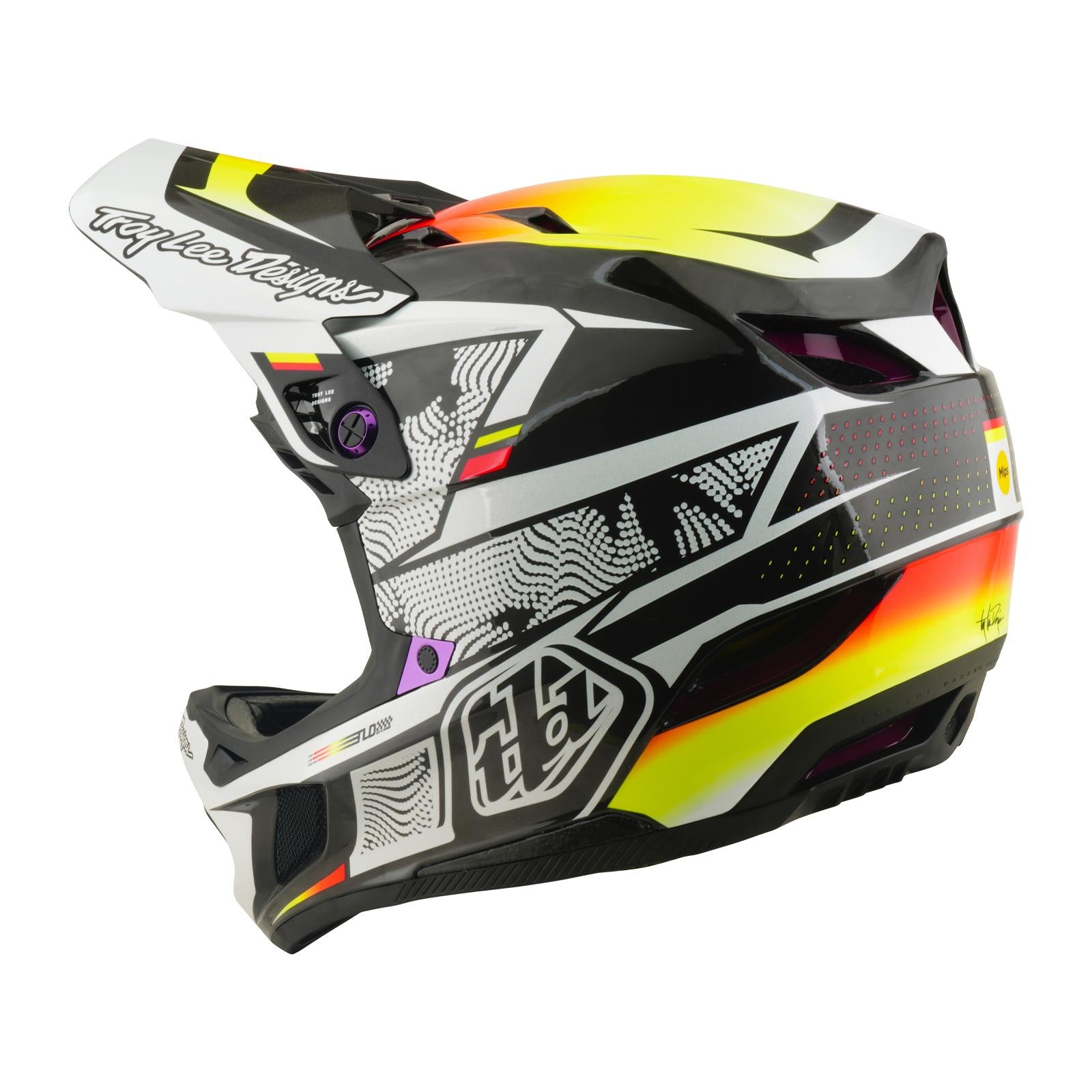 The TLD 26.1 D4 AS Carbon Helmet / Lined Up is a full-face motocross helmet with Mips protection, a visor, and bold black, white, yellow, and orange graphics.