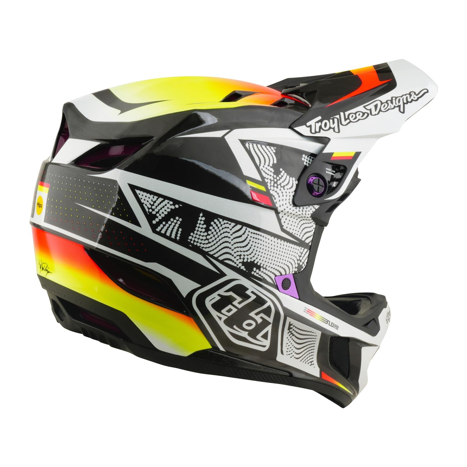 The TLD 26.1 D4 AS Carbon Helmet / Lined Up is a full-face helmet with bold black, white, yellow, and red graphics, a "Troy Lee Designs" logo on the side, and Mips protection for added safety.