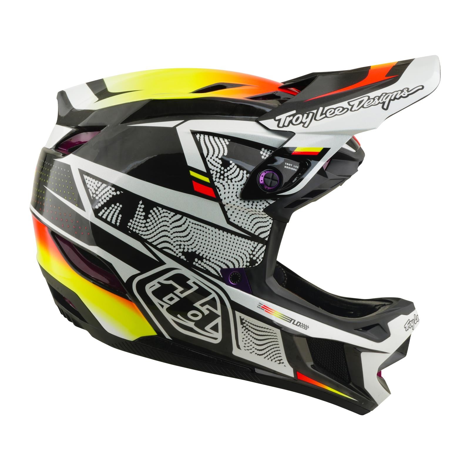 The TLD 26.1 D4 AS Carbon Helmet / Lined Up is a full-face helmet with a visor, black, white, yellow, and orange graphics, and the Troy Lee Designs logo—perfect for motocross or mountain biking.