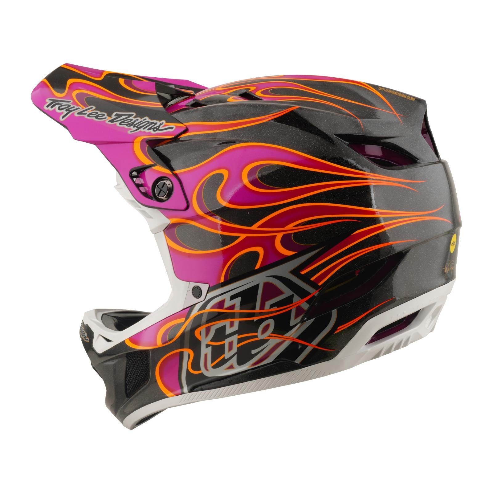 The TLD 26.1 D4 AS Carbon Helmet in Torched Carbon/Magenta is a full-face mountain biking helmet featuring a carbon fiber shell, black-white-pink design, orange flame graphics, and “Troy Lee Designs” on the rear visor.