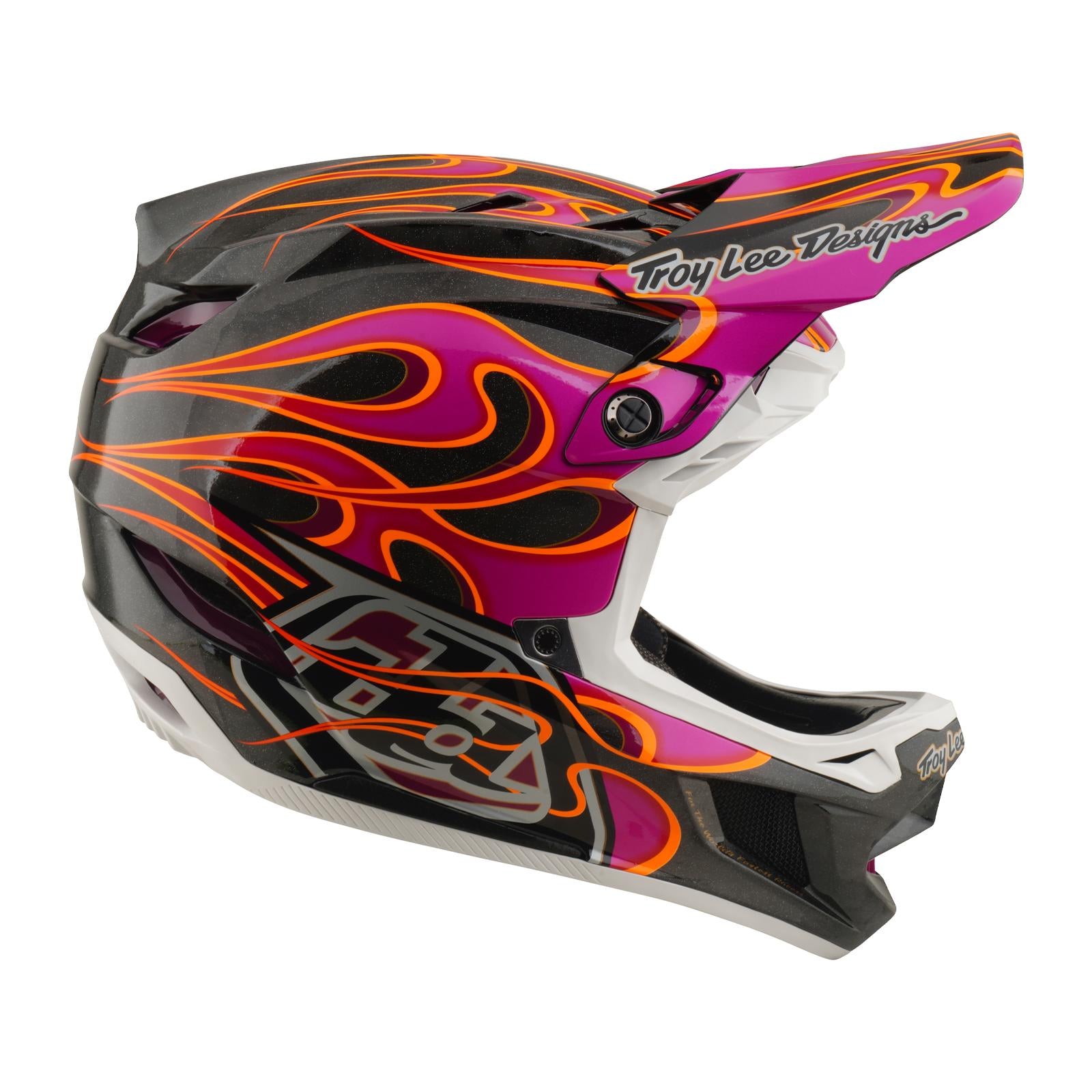 Side view of the TLD 26.1 D4 AS Carbon Helmet in Torched Carbon/Magenta, showcasing a black, pink, and orange flame design, "Troy Lee Designs" branding on the visor, and advanced Mips protection for safety.