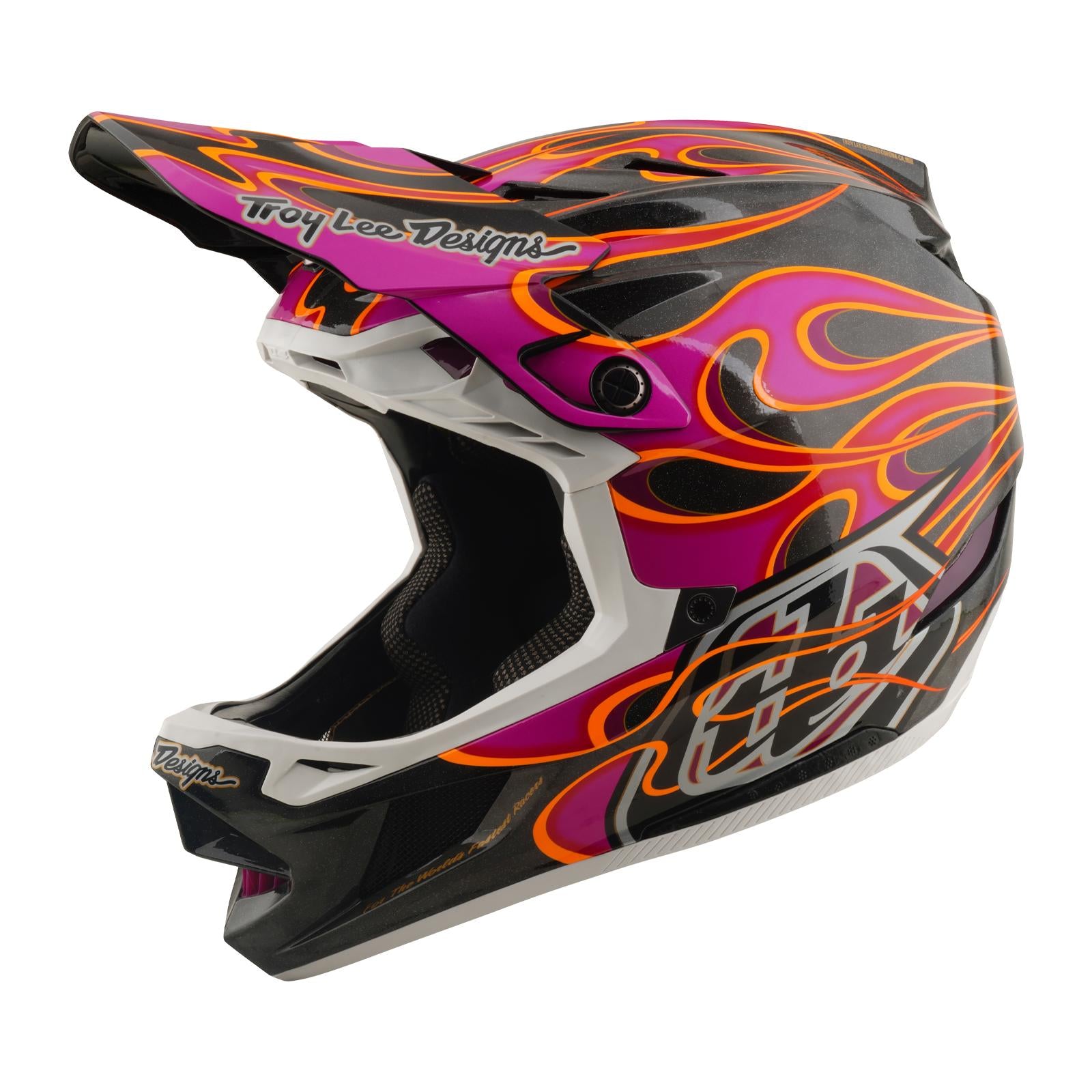 The TLD 26.1 D4 AS Carbon Helmet in Torched Carbon/Magenta is a full-face MTB helmet featuring black carbon, bold pink and orange flames, Mips protection, and "Troy Lee Designs" branding on the visor and chin.