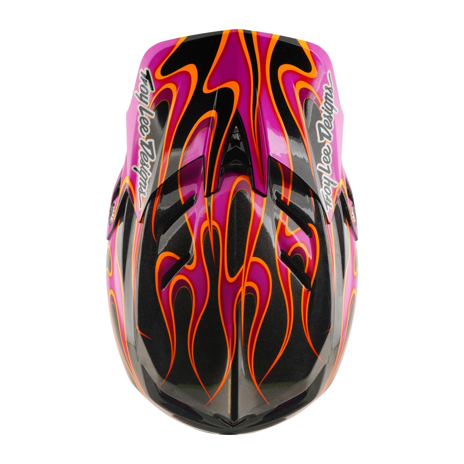 The TLD 26.1 D4 AS Carbon Helmet in Torched Carbon/Magenta features a full-face design with a black base, orange and yellow flame graphics, pink accents, and "Troy Lee Designs" logos on each side, viewed from above.