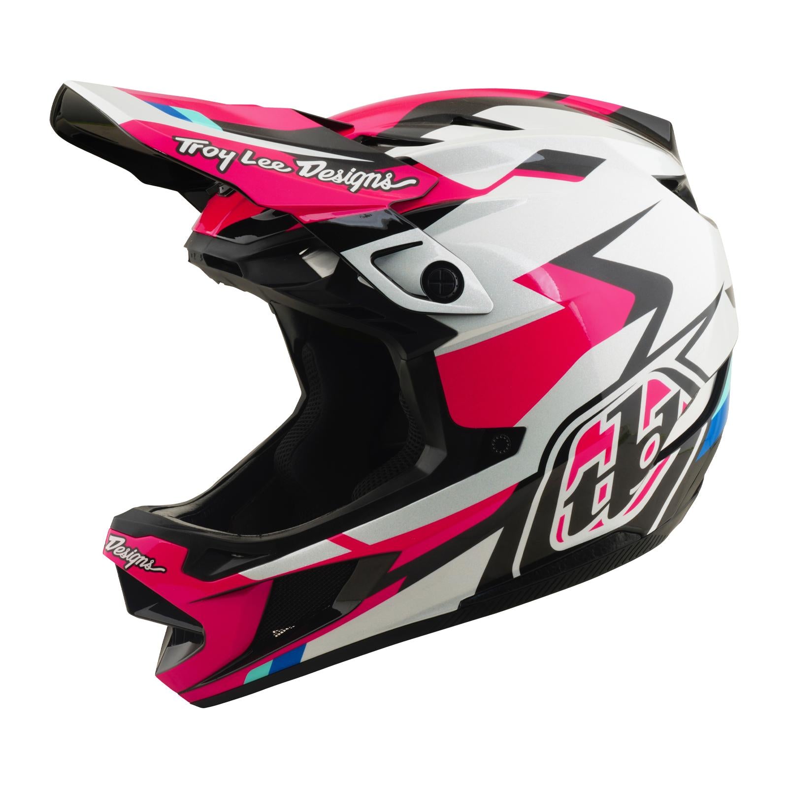 The TLD 26.1 D4 AS Polyacrylite Helmet / Roamer Magenta is a full-face motocross helmet with a pink, white, black, and blue geometric design. It features "Troy Lee Designs" on the visor and is Mips compatible—perfect for mountain biking.