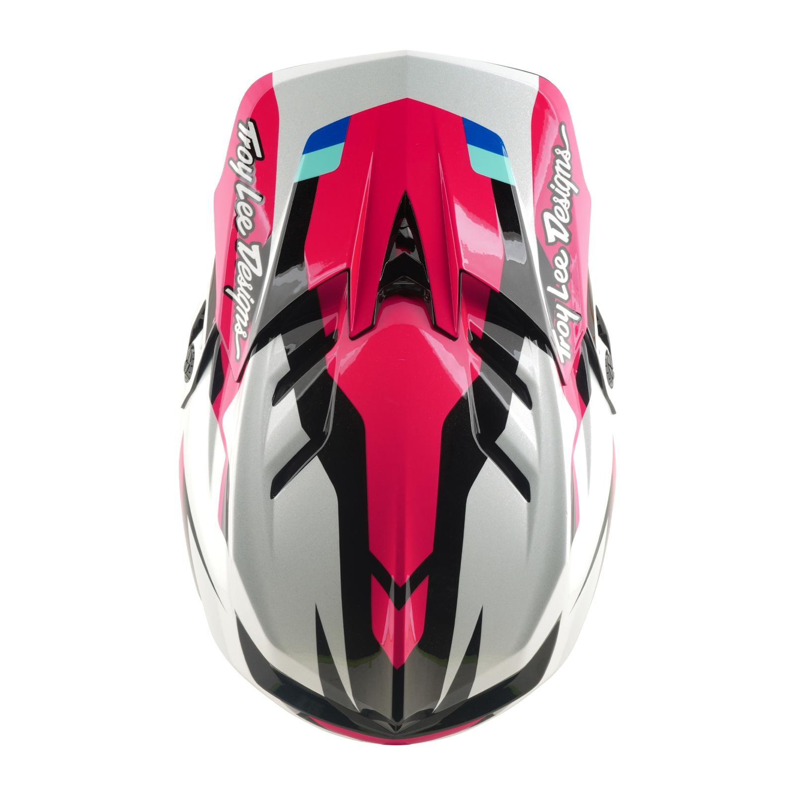 The TLD 26.1 D4 AS Polyacrylite Helmet / Roamer Magenta features a pink, black, white, and blue geometric design, ideal for mountain biking. Seen from the front, it showcases "Troy Lee Designs" branding on both sides.