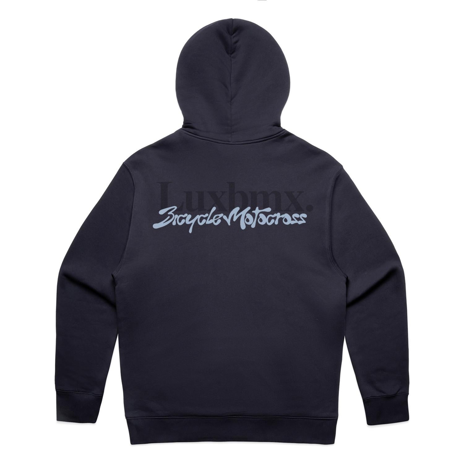 An ink blue LUXBMX Times Neue Hoodie lies flat, displaying the back with "Luxbmx" and "Bicycle Motocross" in large stylized lettering. This heavyweight pullover fleece is ideal for BMX enthusiasts seeking both comfort and style.