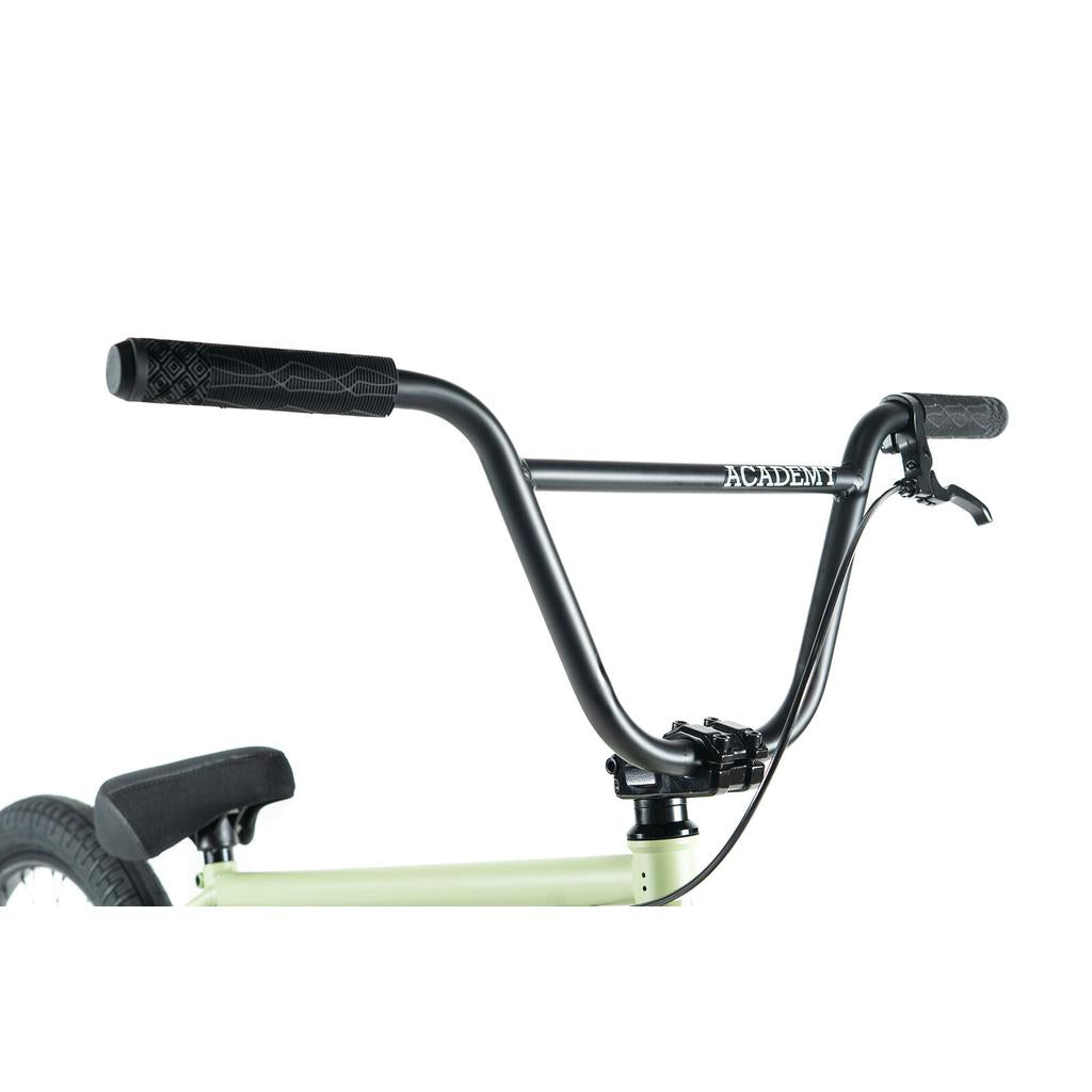 Close-up of Academy Aspire 20 Inch Bike's black CrMo bars with rubber grips, featuring "ACADEMY" logo and brake lever; seat and part of rear wheel with sealed hubs are also partially visible.