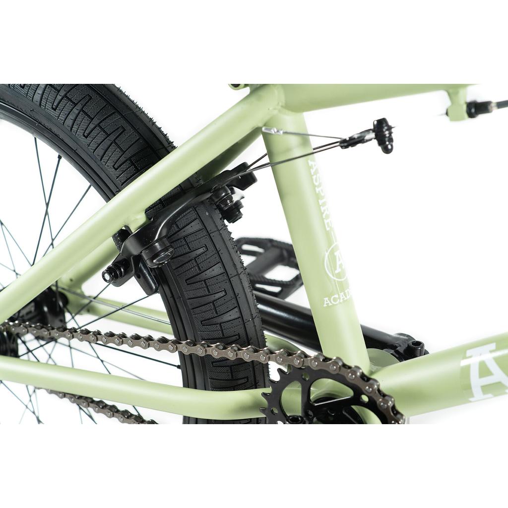 Close-up of the Academy Aspire 20 Inch Bike frame in light green, highlighting the rear tire, chain, sprocket, brake system, and sealed hubs.