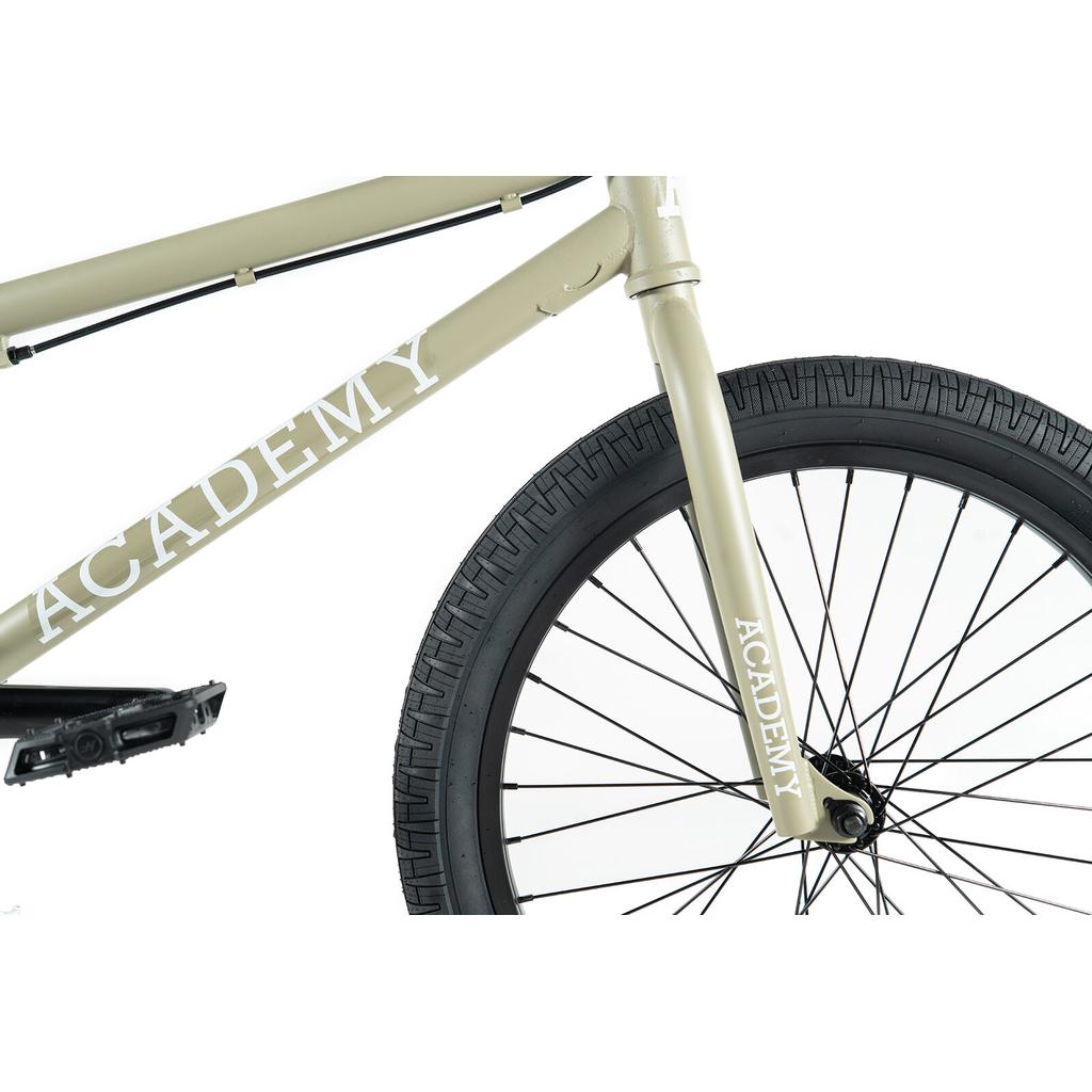 Close-up of the beige Academy Entrant 20 Inch Bike highlighting the front tire, fork, pedal, and frame with "ACADEMY" branding—an ideal entry-level BMX for freestyle riding.